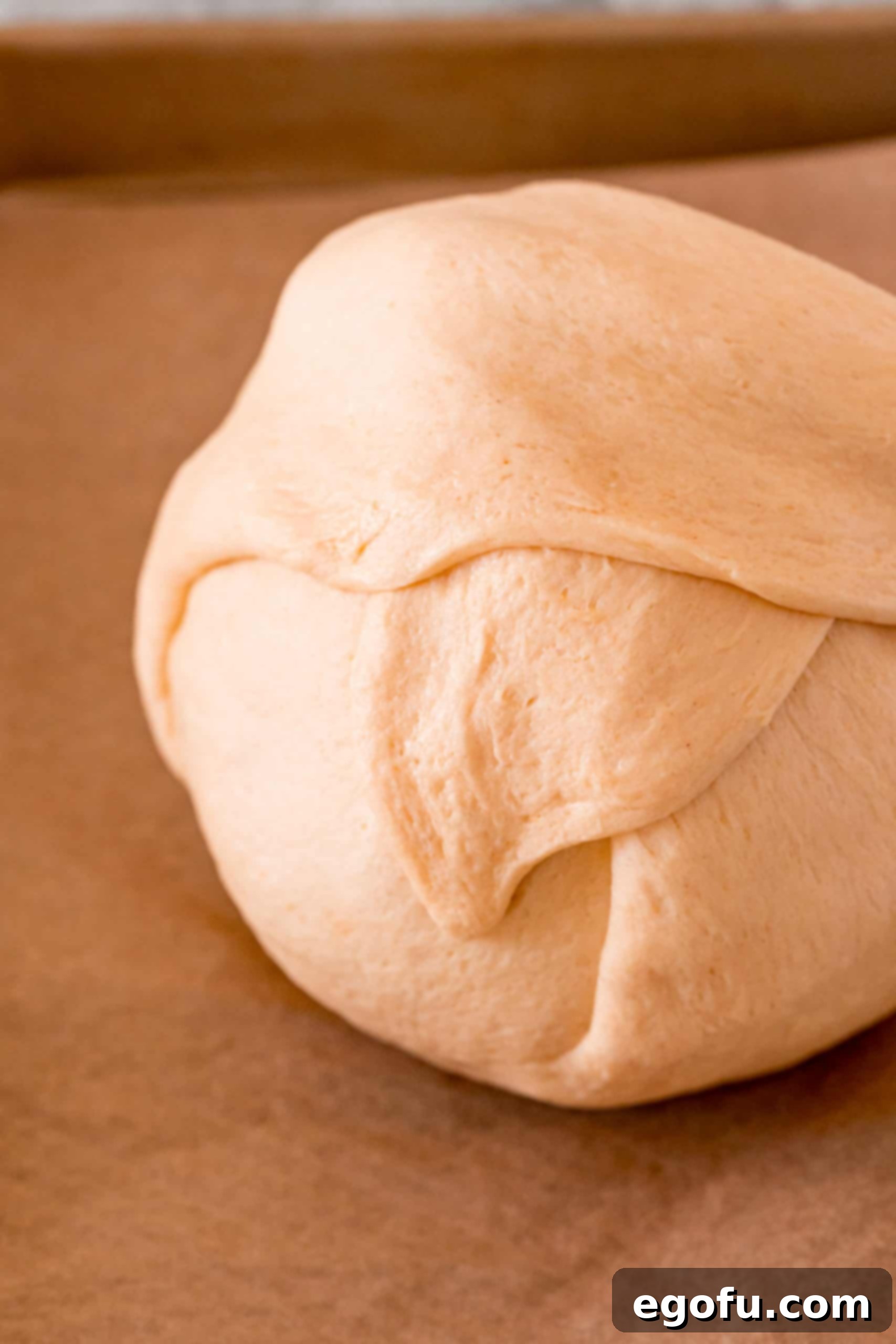 The crescent dough carefully wrapped around the savory chicken mixture, with seams pinched together, creating a perfectly enclosed ball ready for baking.