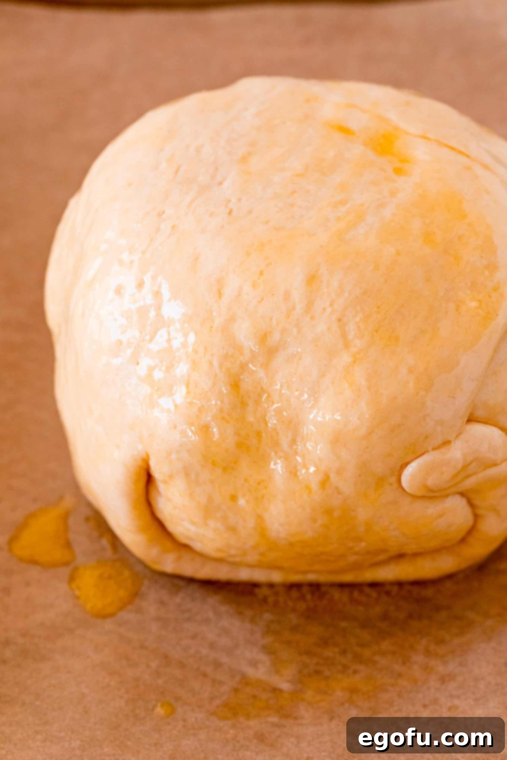 The Crack Chicken Ball, perfectly formed and brushed with melted butter, sitting on a baking sheet, ready to go into the oven for baking.