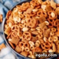 Overhead close-up of The Best Party Chex Mix in a festive bowl, showcasing its diverse textures and appealing golden hue, ready to be enjoyed.