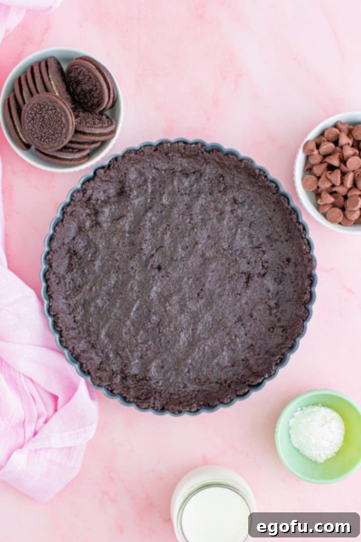 Decadent Raspberry Chocolate Tart 6 Oreo crust mixture being pressed evenly into a tart pan.
