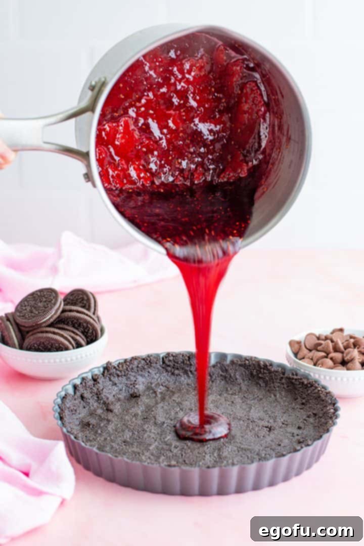 Decadent Raspberry Chocolate Tart 7 Thickened raspberry mixture being poured over the Oreo crust in the tart pan.