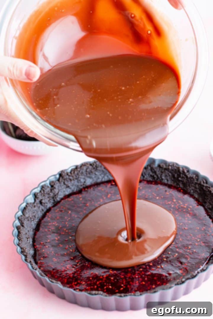 Decadent Raspberry Chocolate Tart 10 Smooth chocolate ganache being poured over the raspberry layer in the tart.