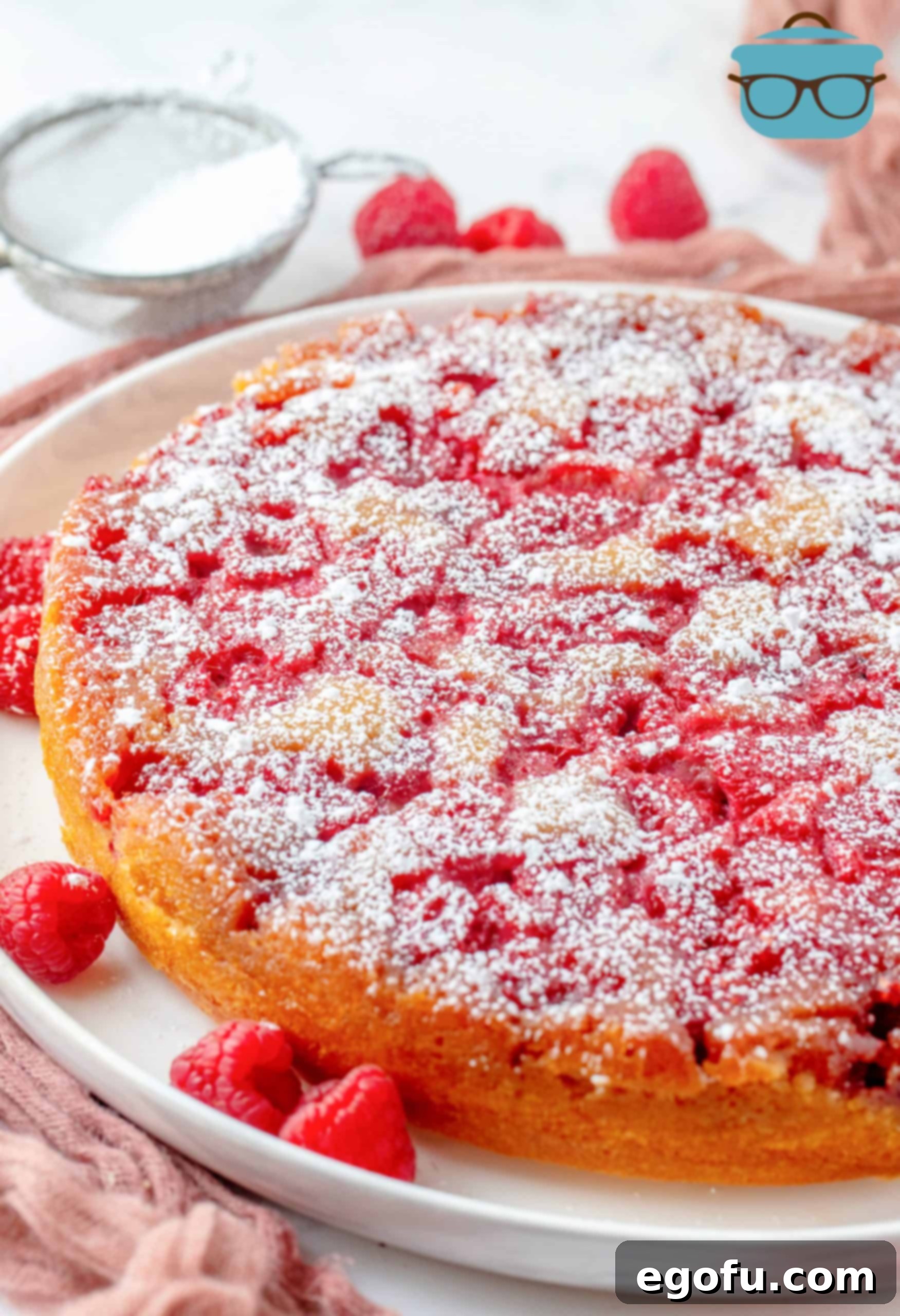 Crimson Raspberry Flip Cake 18 Upside Down Raspberry Cake on white platter topped with powdered sugar.