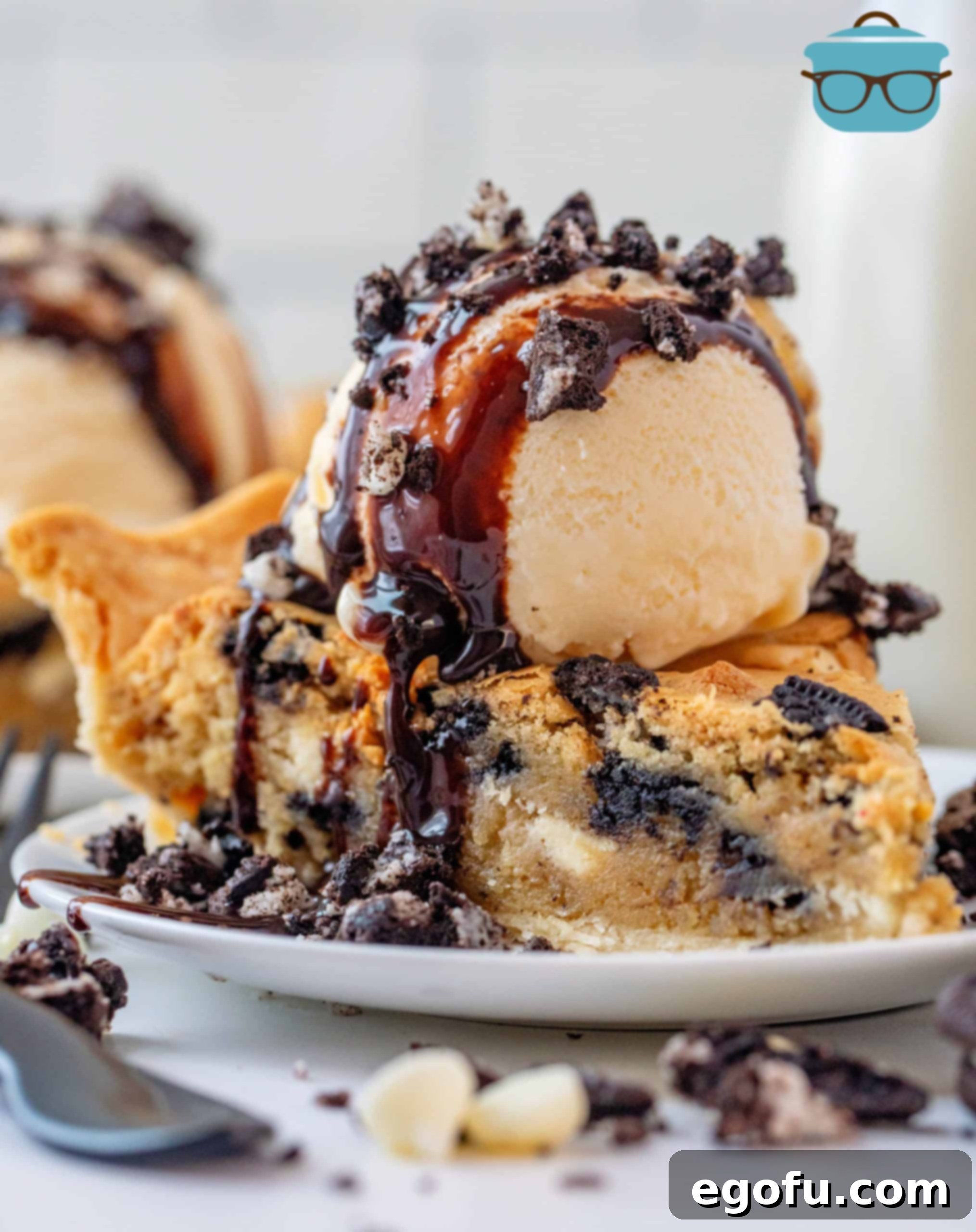 Oreo Cookie Pie on plate topped with ice cream, chocolate syrup and crushed Oreos.