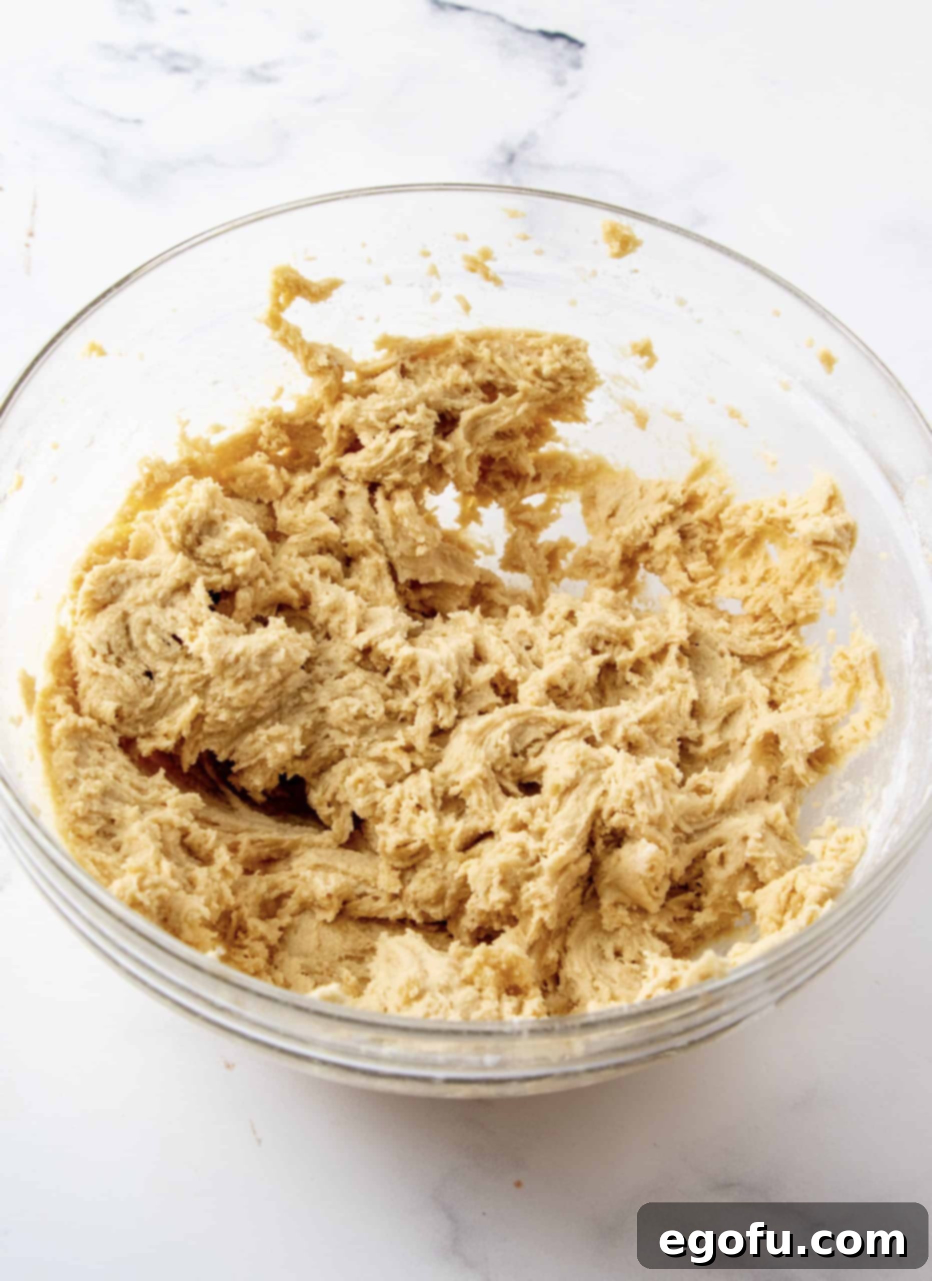 Flour mixed into mixture creating batter in a bowl.