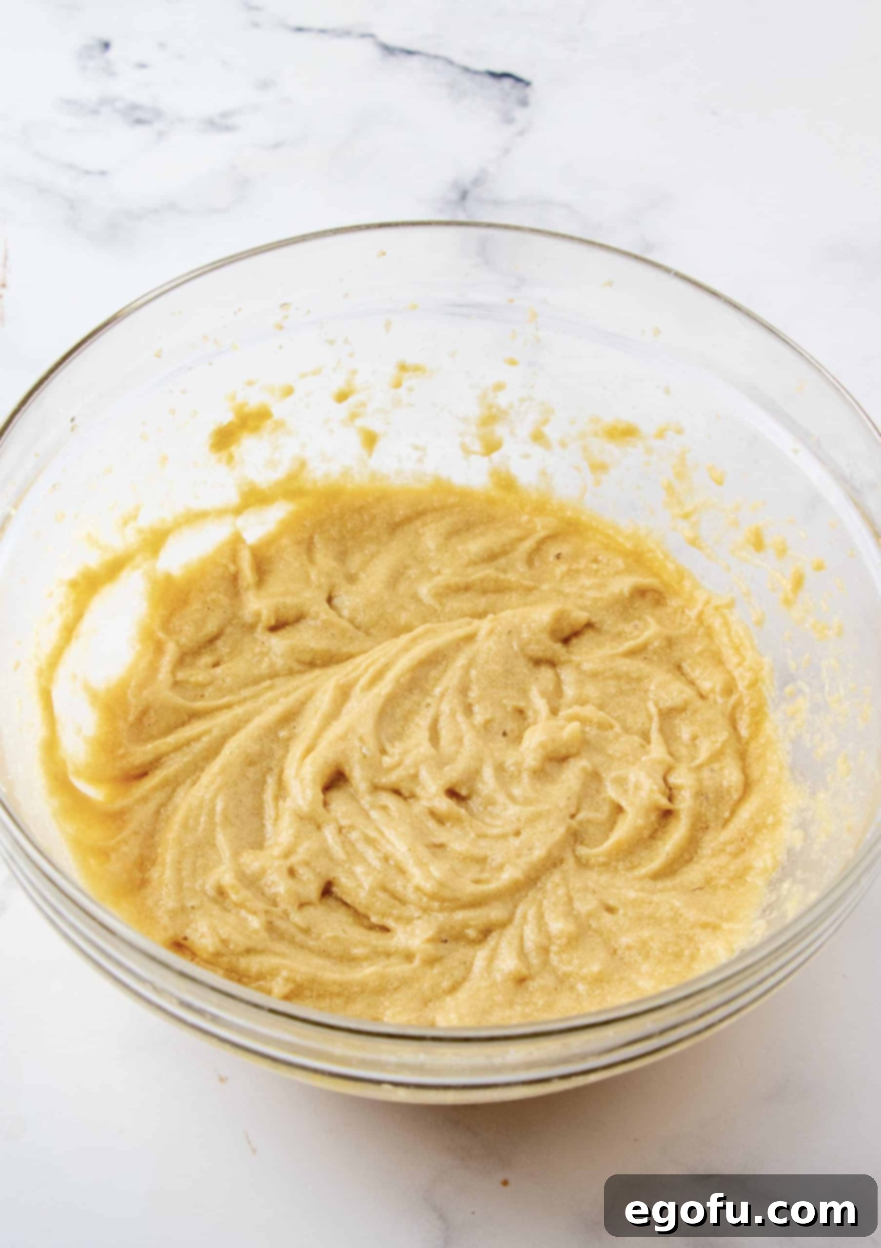 Eggs mixed into butter mixture in a clear bowl.