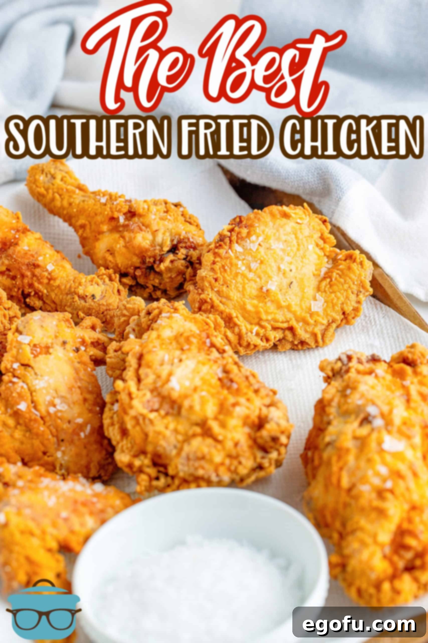 fried chicken pieces shown on a paper towel with a small bowl of sea salt to the side.