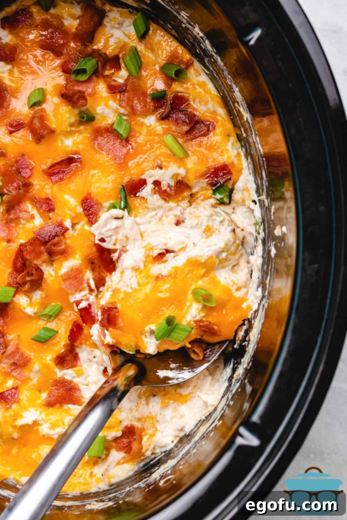 Crack Chicken in Crock Pot with spoon in mixture lifting out a serving.