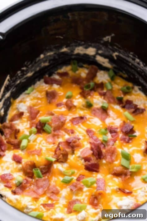 Melted cheese with bacon and green onions in crock pot on top of chicken