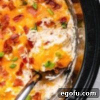 Close up of spoon in Crack Chicken mixture in crock pot