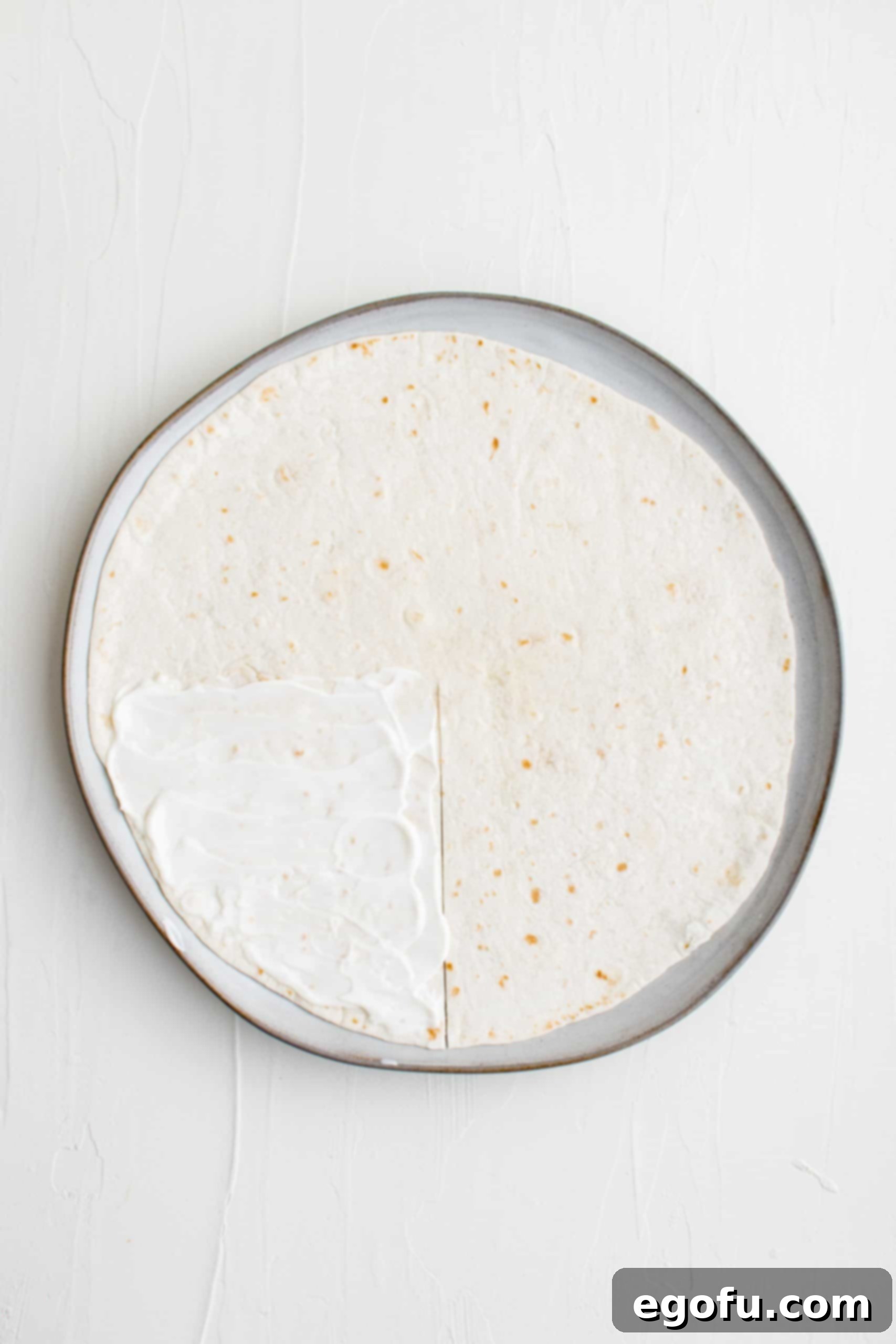 Tortilla on plate with a single slit cut from the center to the edge.