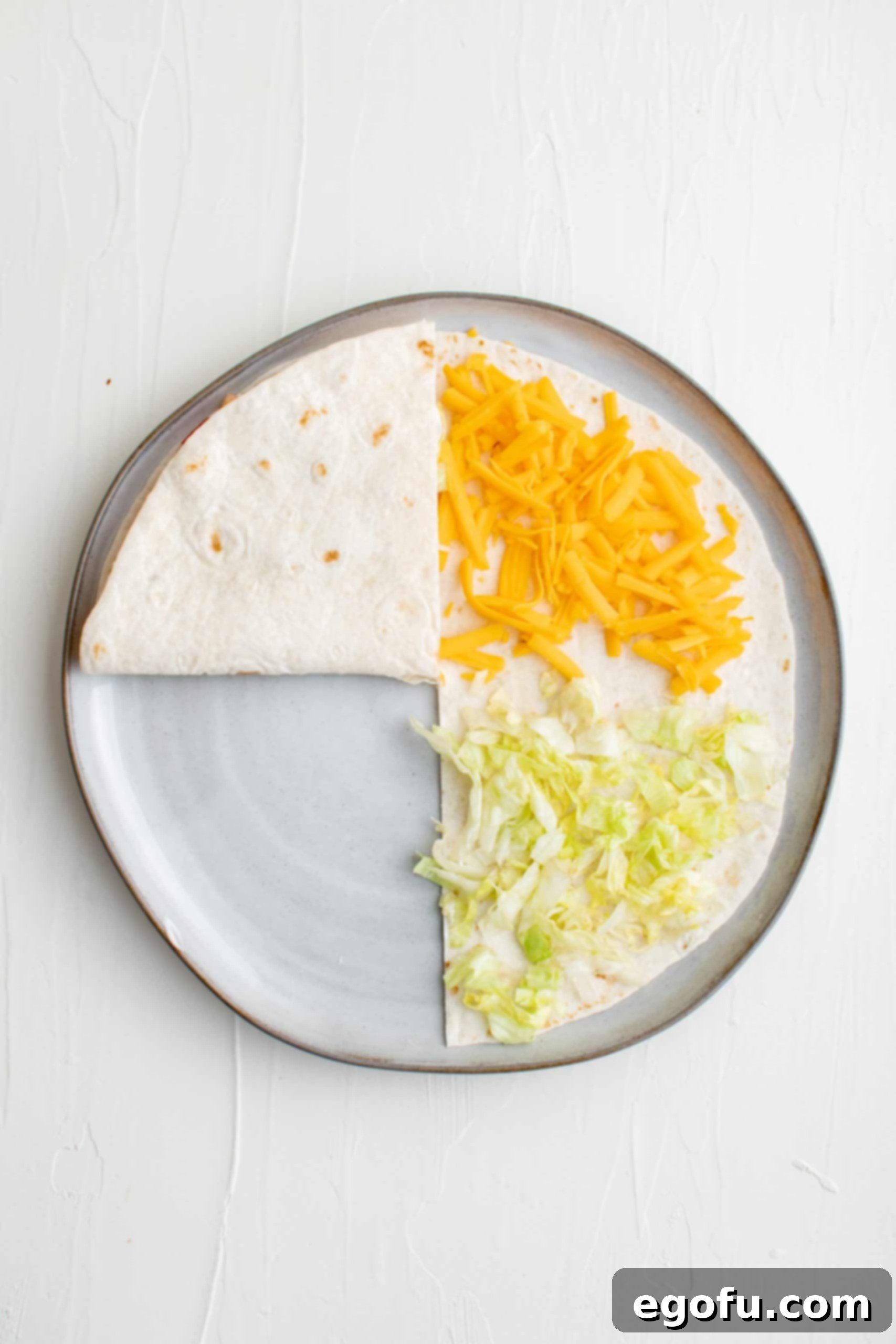 The first fold: bacon quadrant flipped onto the tomato quadrant on the tortilla.