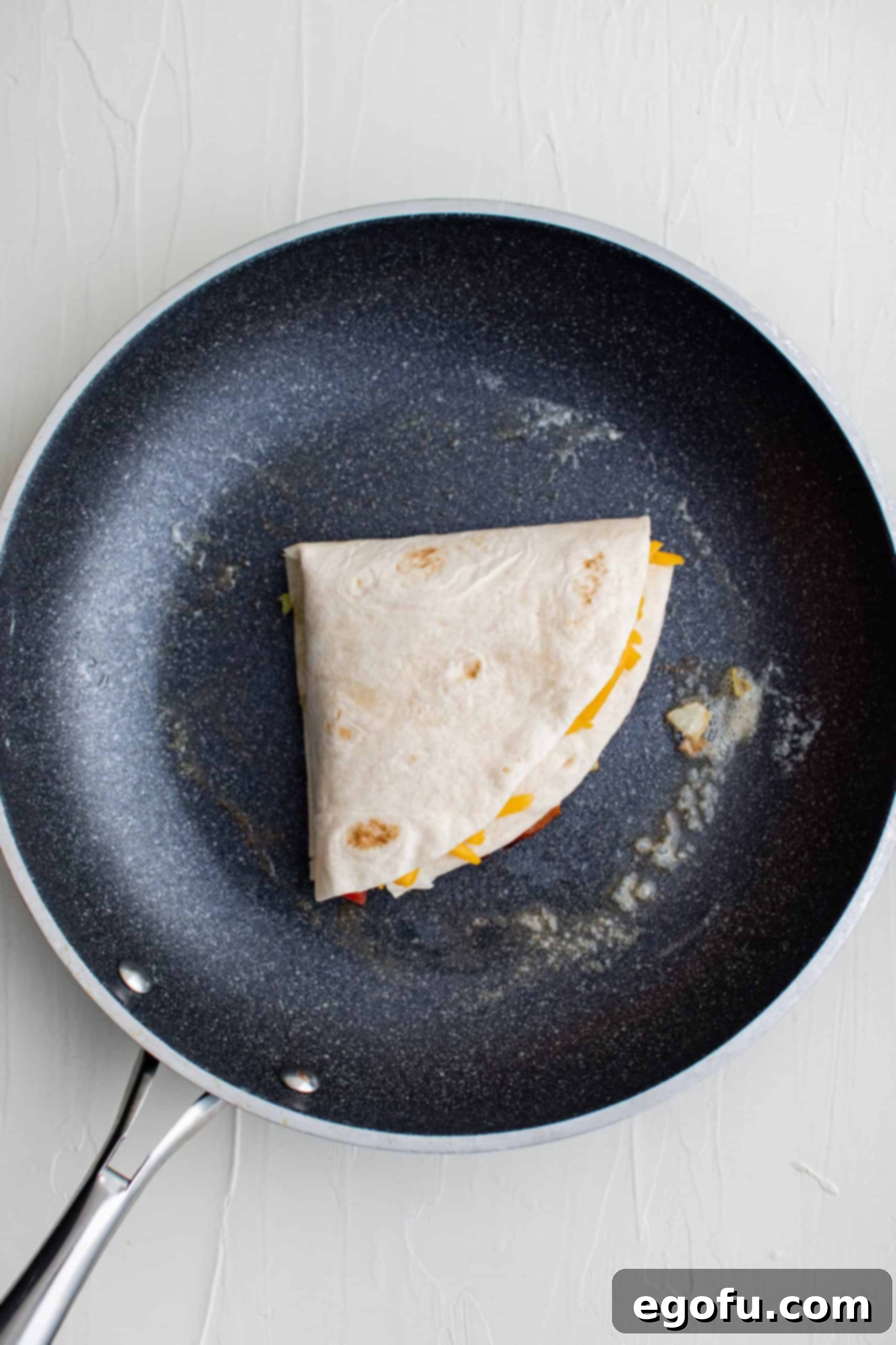 BLT Quesadilla cooking in a frying pan, starting to brown.