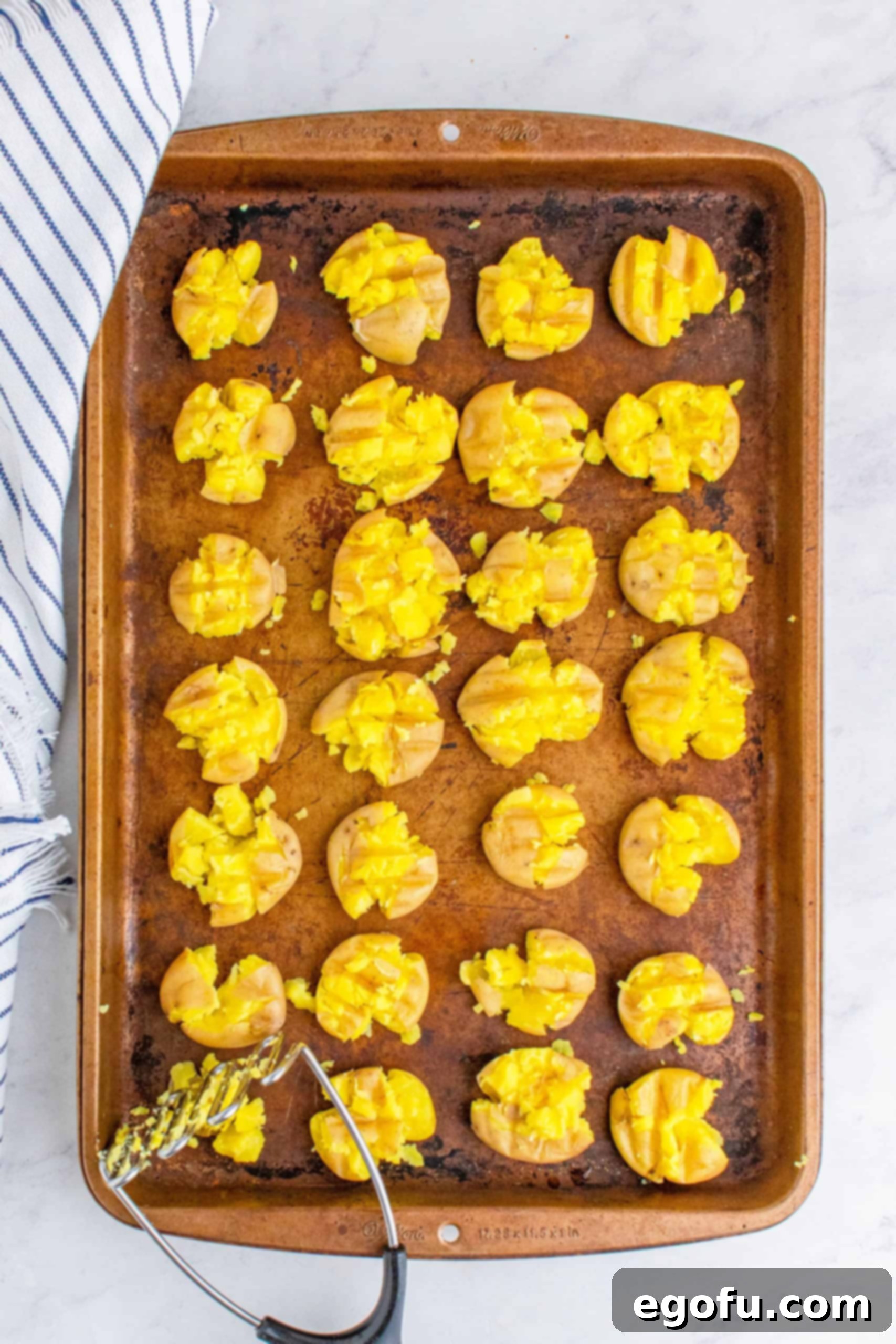 Overhead of potatoes being smashed with a potato masher.