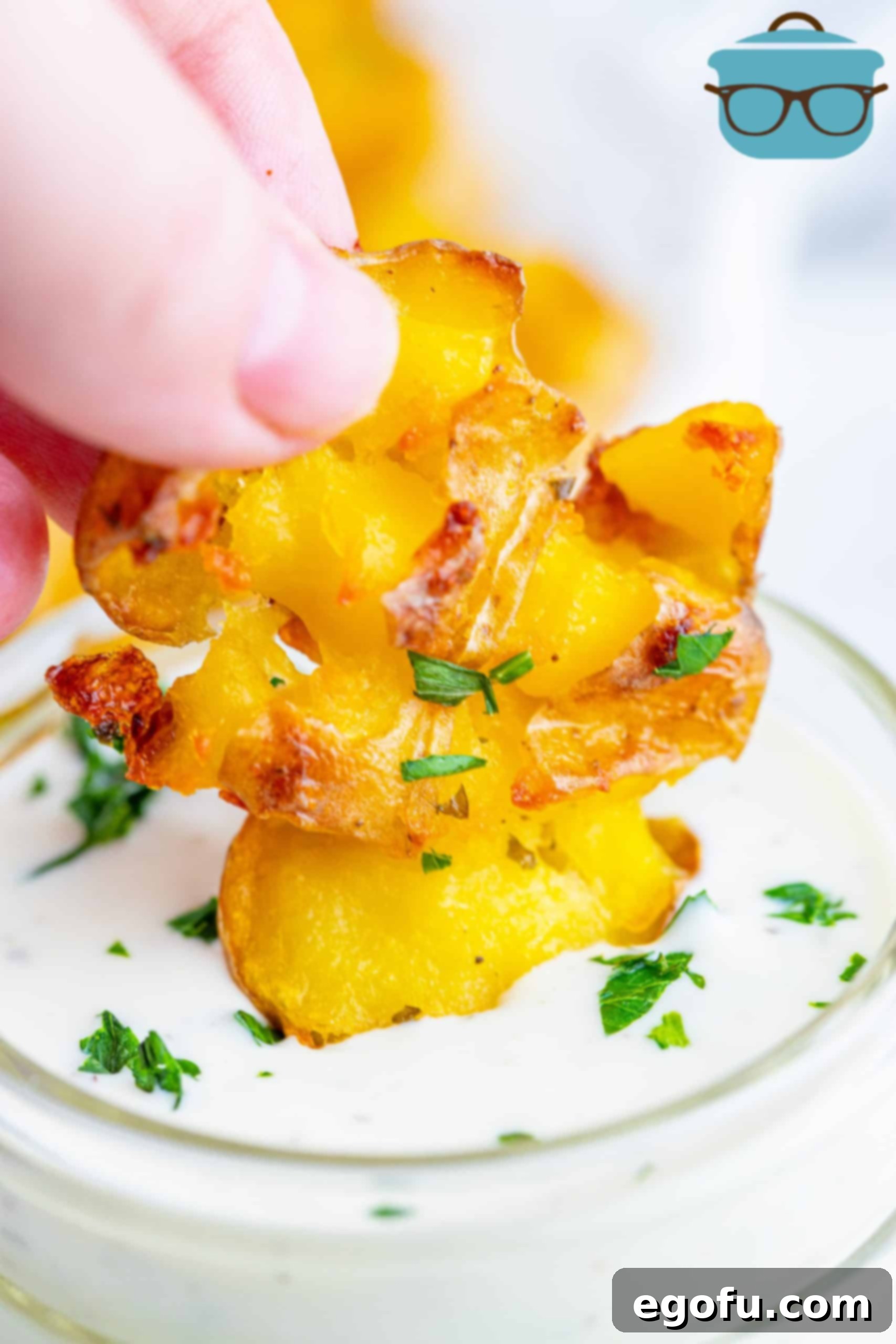 Hand dipping one Smashed Potato into ranch.