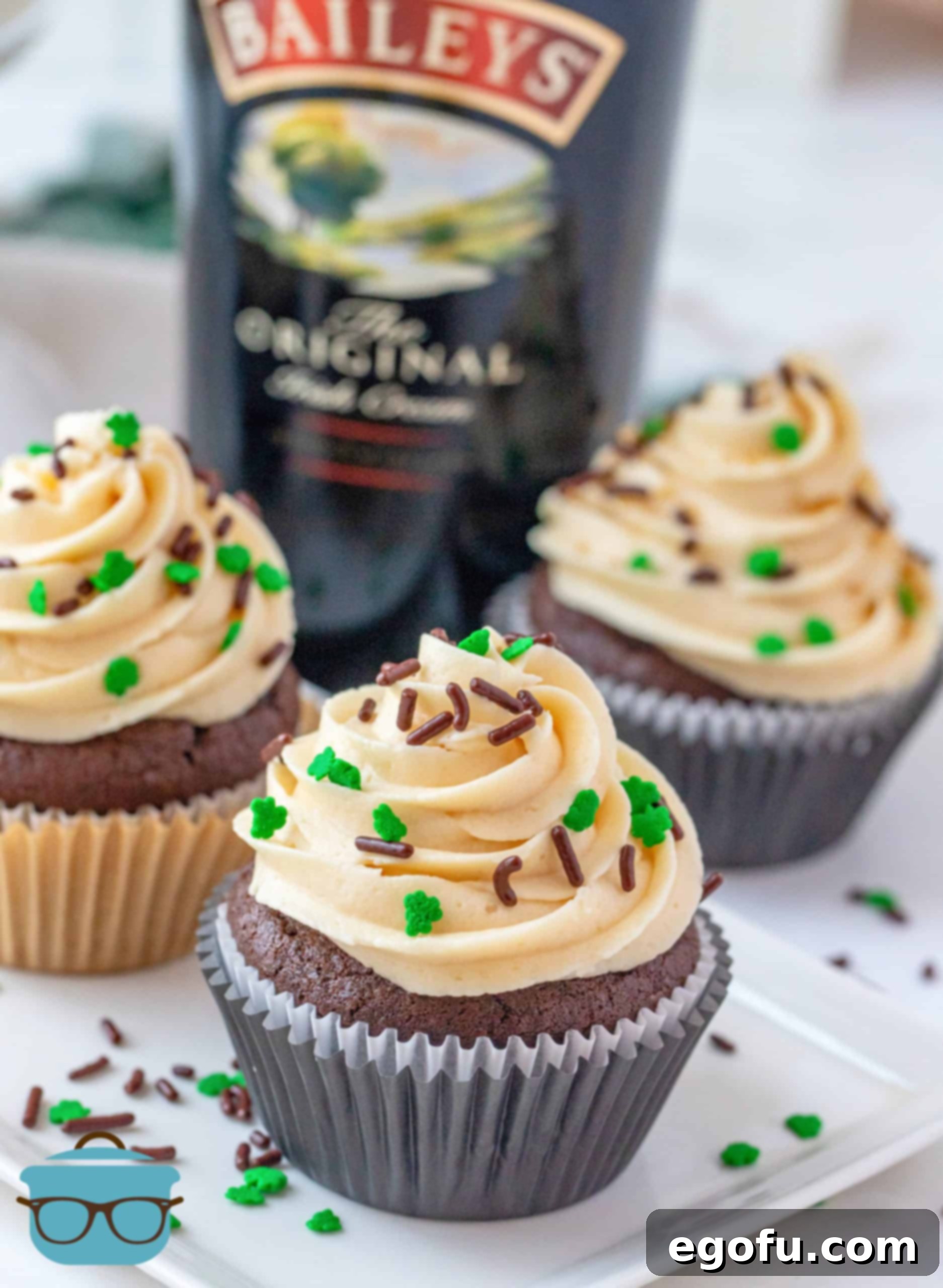 Decadent Baileys Cupcakes 2 Homemade Baileys Cupcakes on white platter with sprinkles, showcasing their rich chocolate color and creamy frosting.