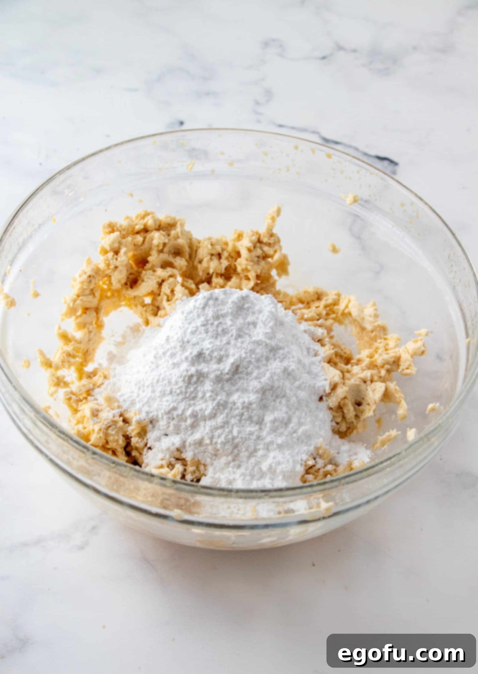 Decadent Baileys Cupcakes 12 Powdered sugar being added incrementally to the beaten butter and Baileys mixture, gradually thickening into a rich buttercream frosting.