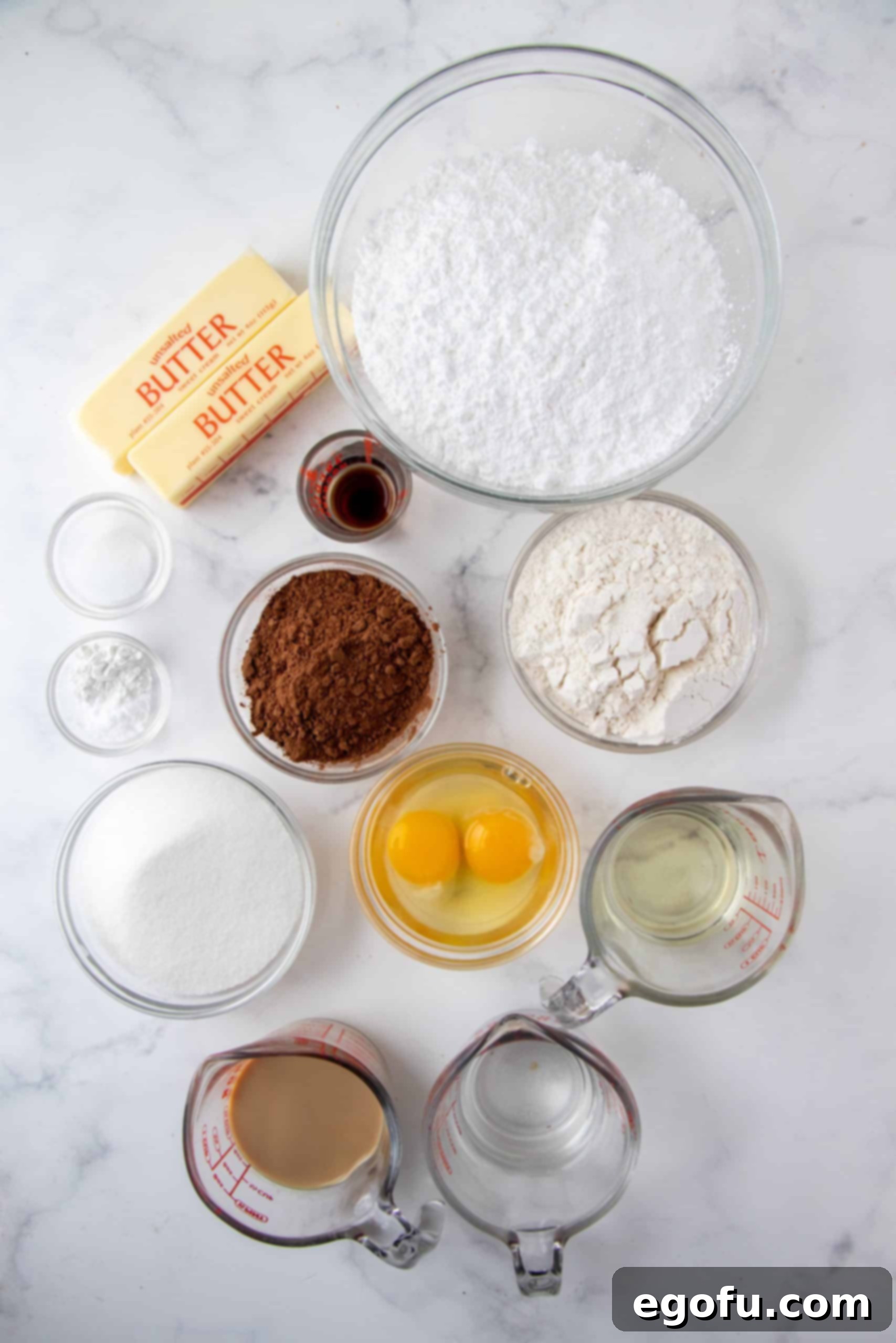 Decadent Baileys Cupcakes 4 All the essential ingredients for Homemade Baileys Cupcakes laid out: all-purpose flour, sugar, cocoa powder, baking powder, baking soda, salt, vanilla extract, eggs, Baileys Irish Cream, water, oil, butter, and powdered sugar.