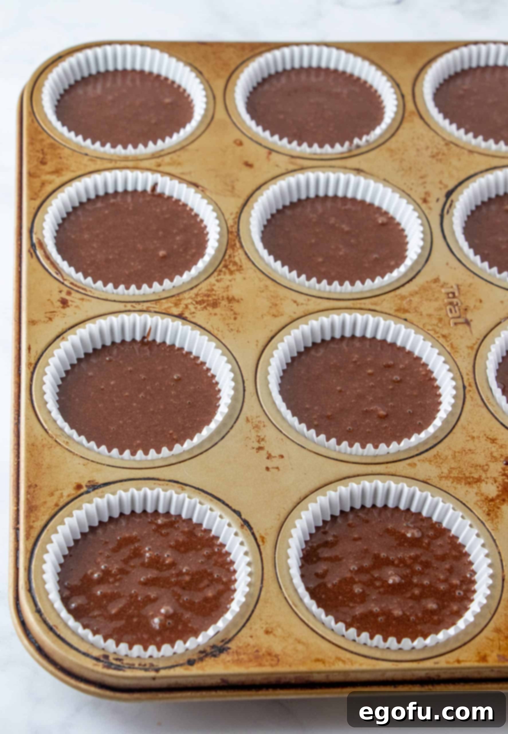 Decadent Baileys Cupcakes 9 Cupcake batter neatly filled into paper liners within a muffin tin, arranged in even portions before baking.