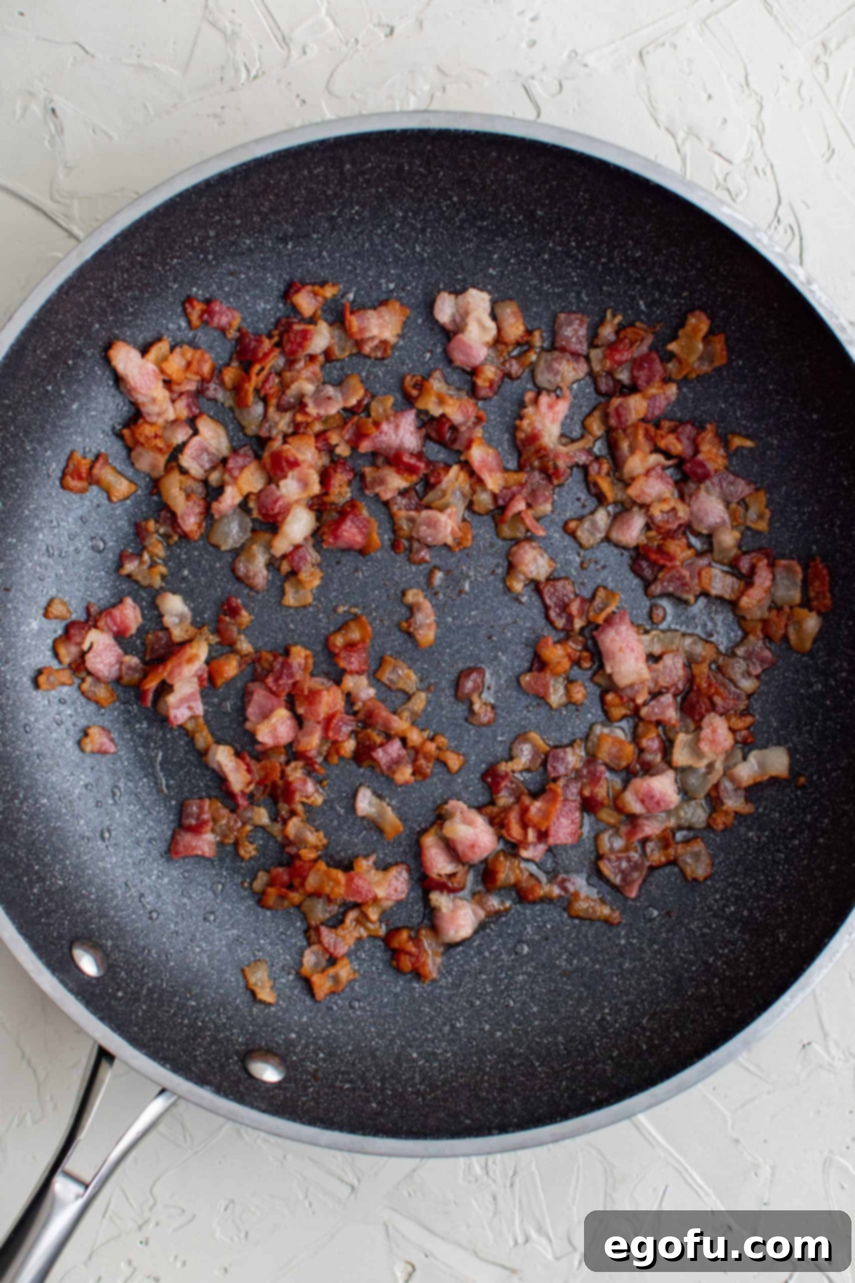 Cooked and crumbled bacon in a skillet. 