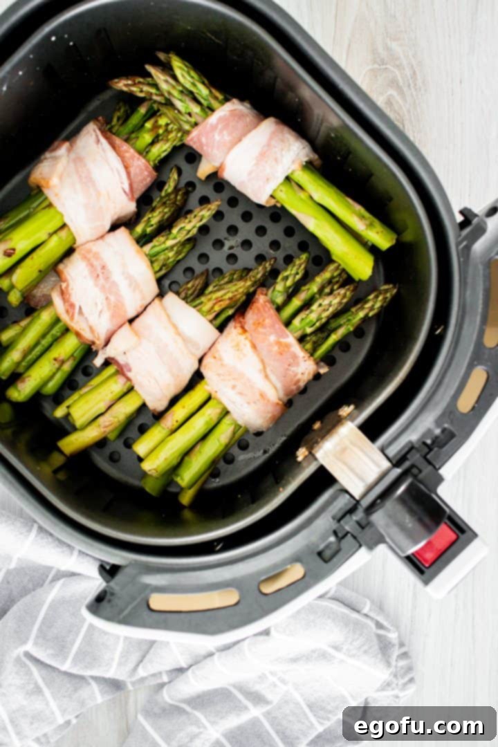 Crispy Air Fryer Bacon Asparagus Bundles 8 Bacon wrapped asparagus uncooked in air fryer.
