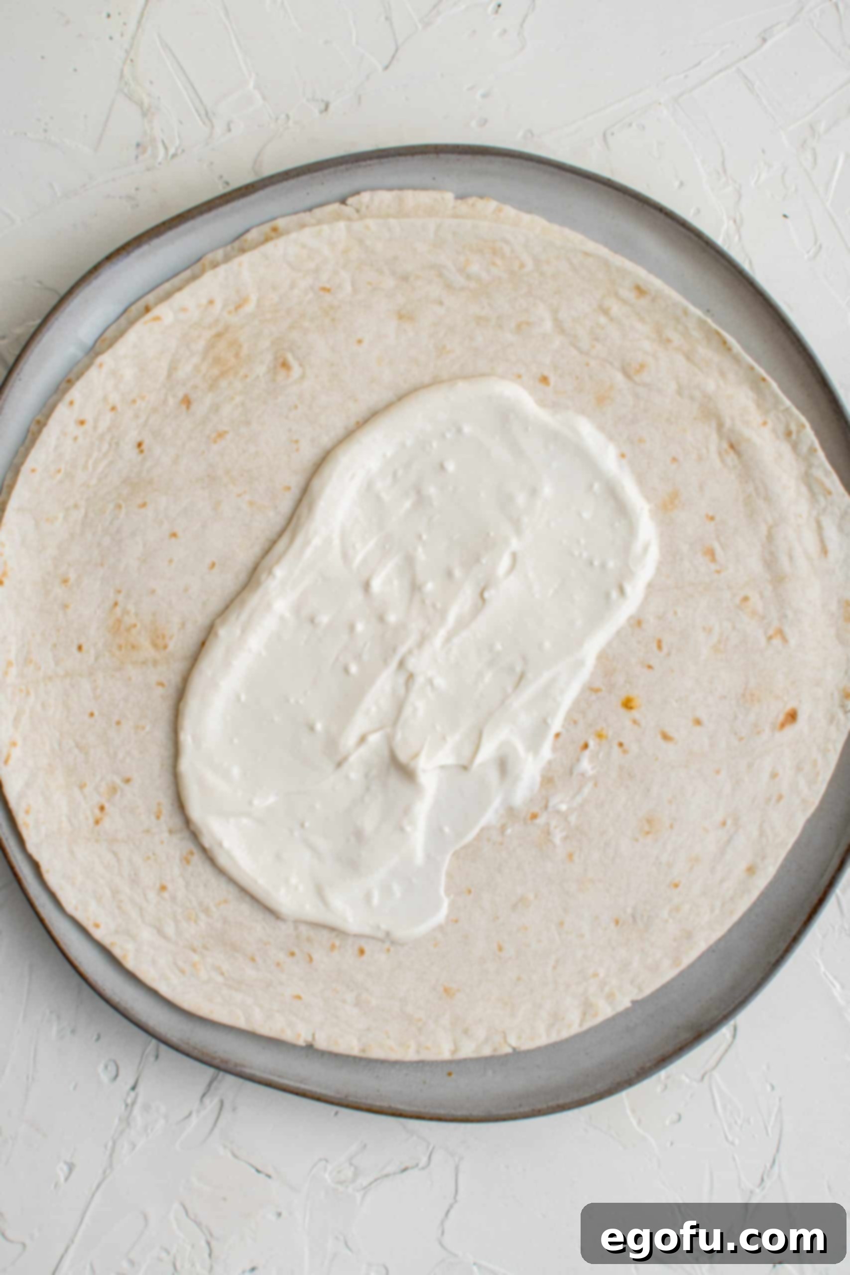Sauce spread in center of one tortilla.