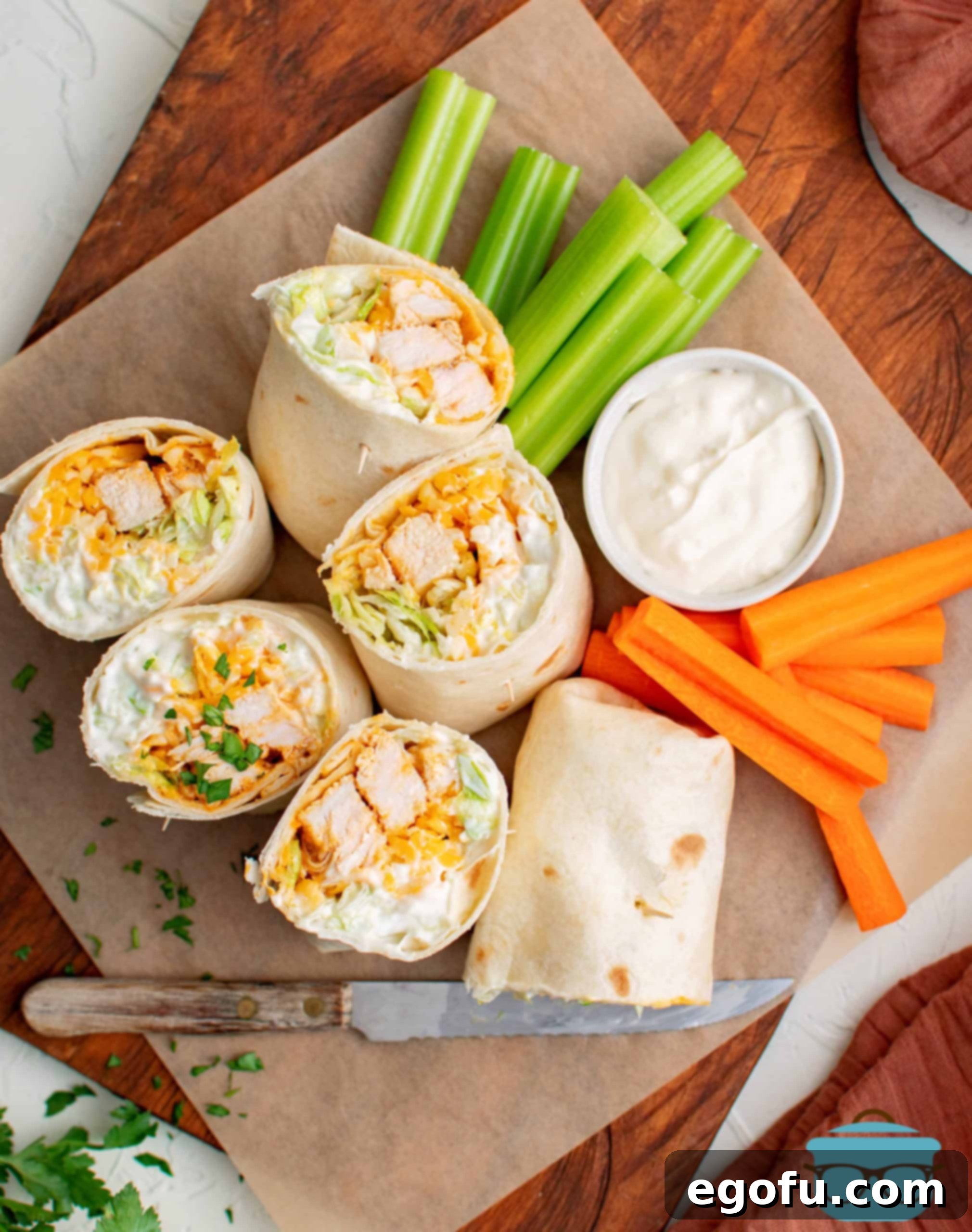Overhead photo of cup open Buffalo Chicken Wraps with dipping sauce, celery and carrot sticks.