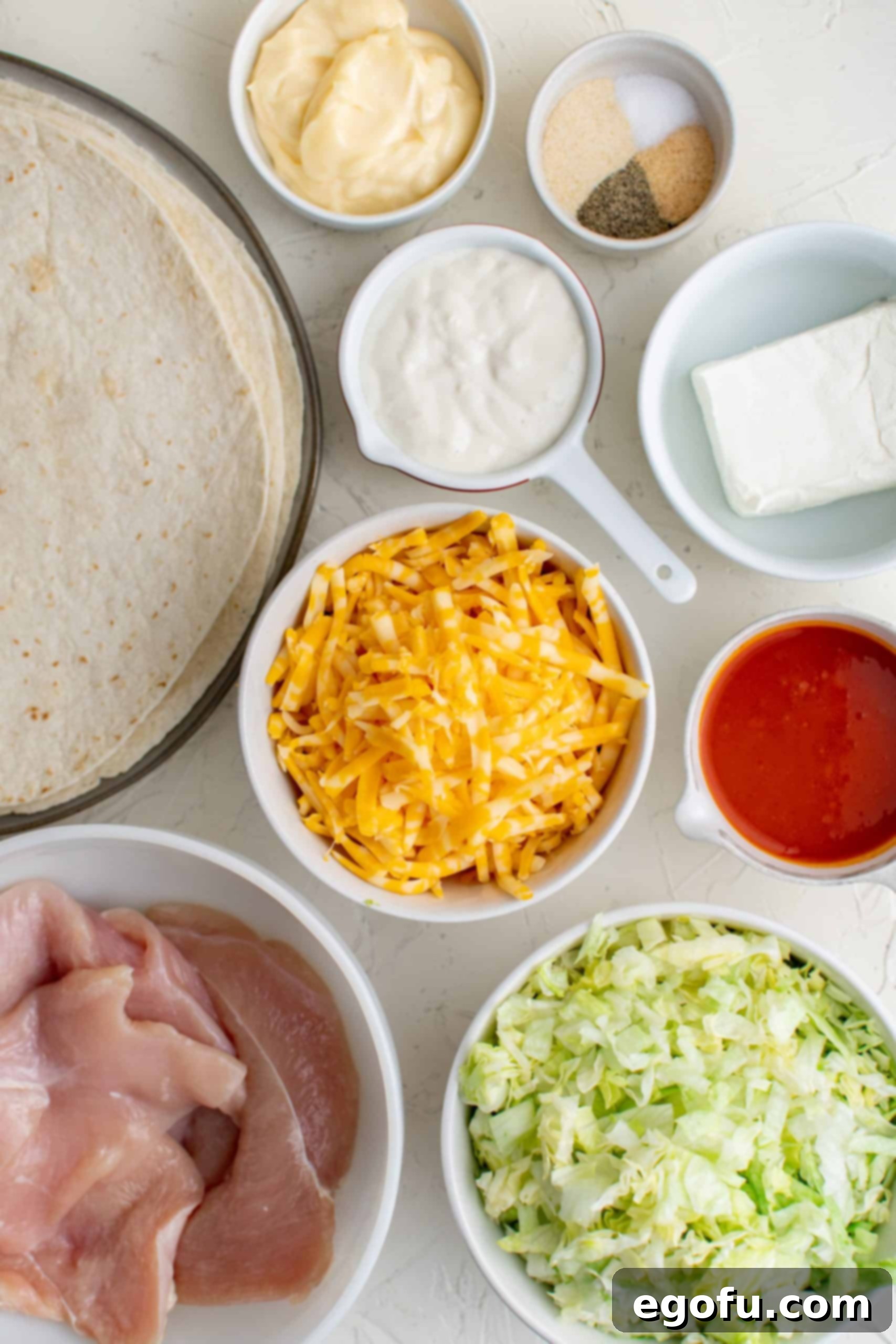 Ingredients needed to make a Buffalo Chicken Wrap: chicken breasts, hot sauce, garlic powder, onion powder, salt, pepper, cream cheese, mayonnaise, blue cheese dressing, tortillas, shredded lettuce, cheese.