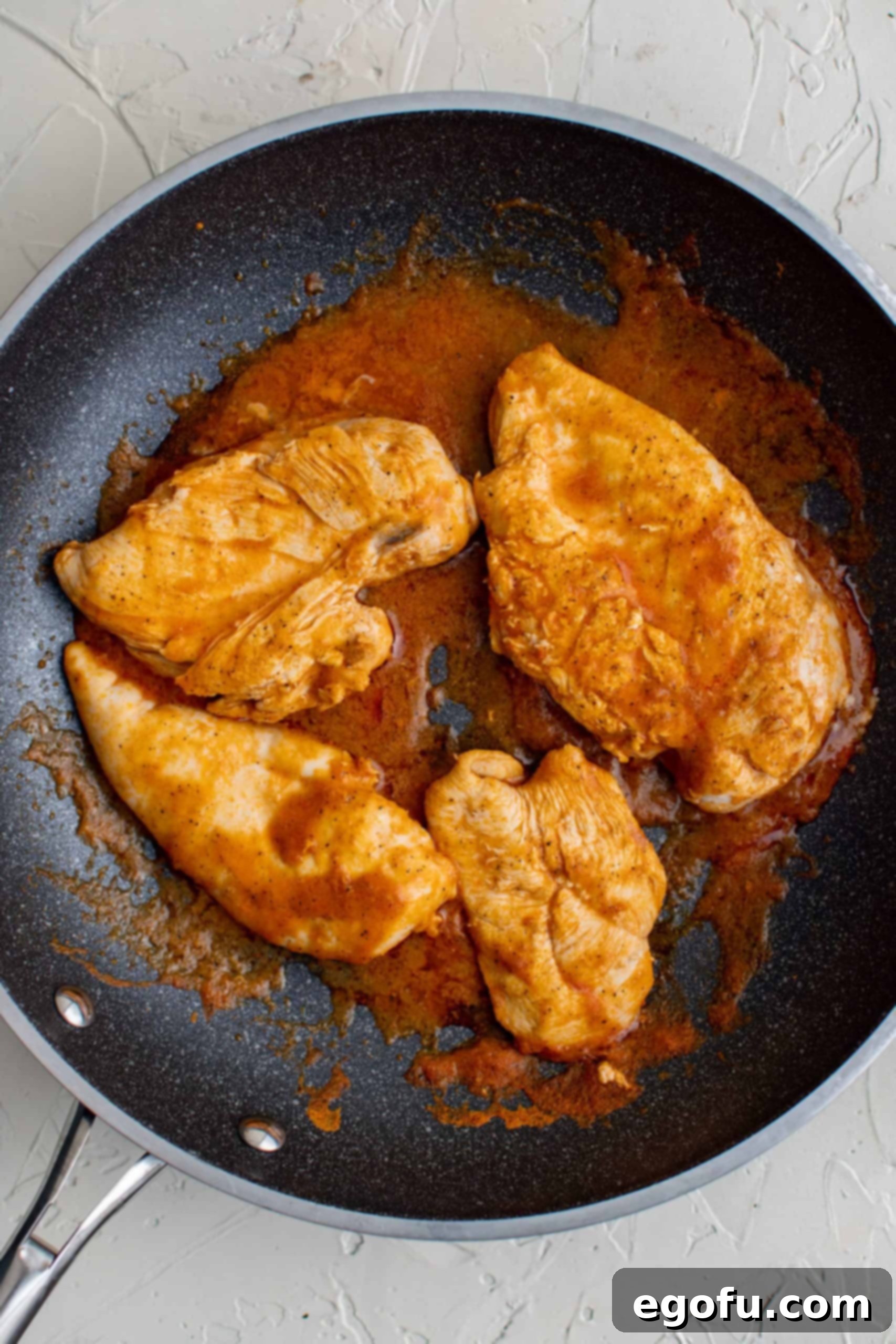 seasoned chicken breasts cooking in a skillet.