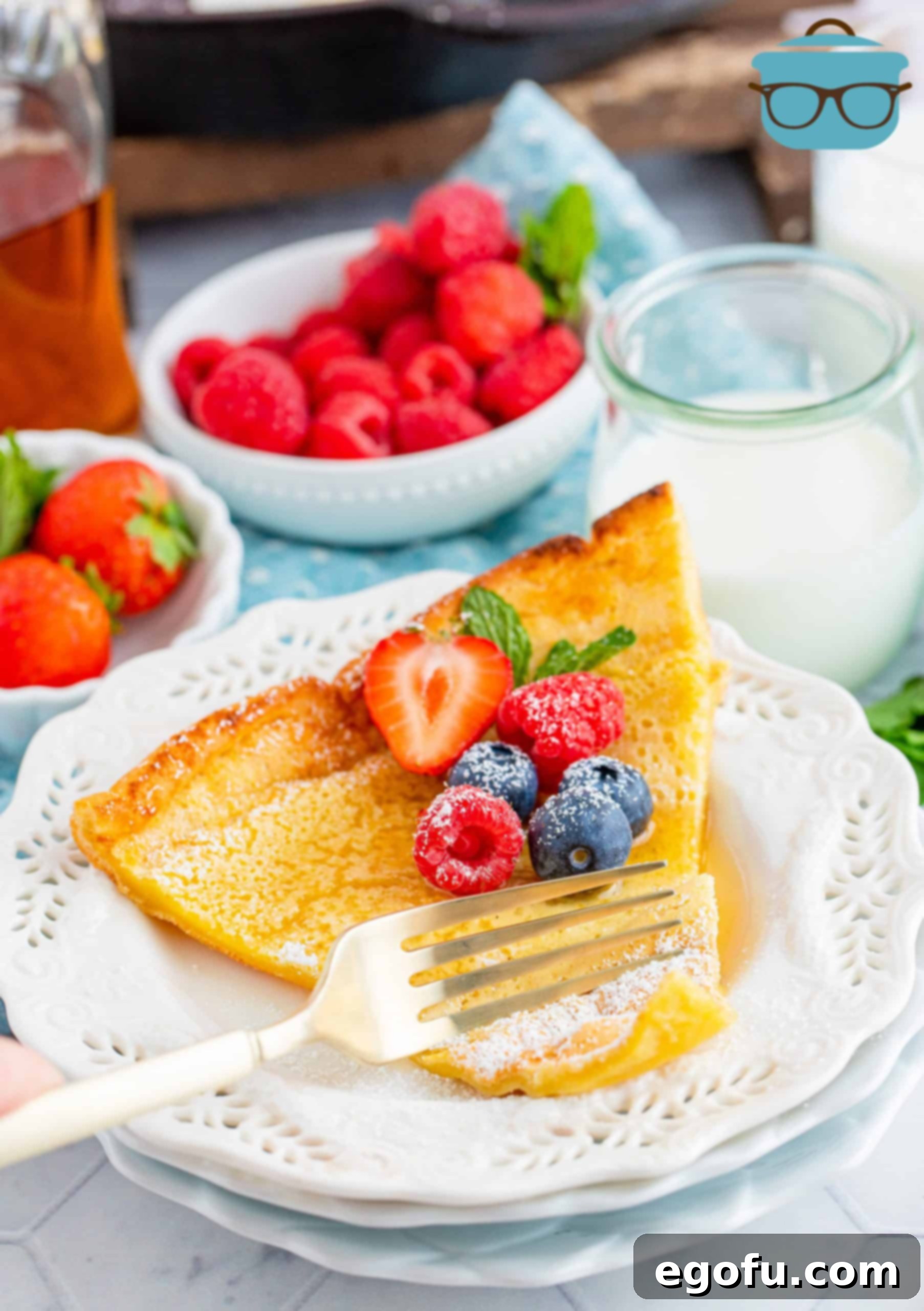 Oven Baked Cloud Pancake 2 Slice of Dutch Baby Pancake on white plate topped with fruit and syrup.