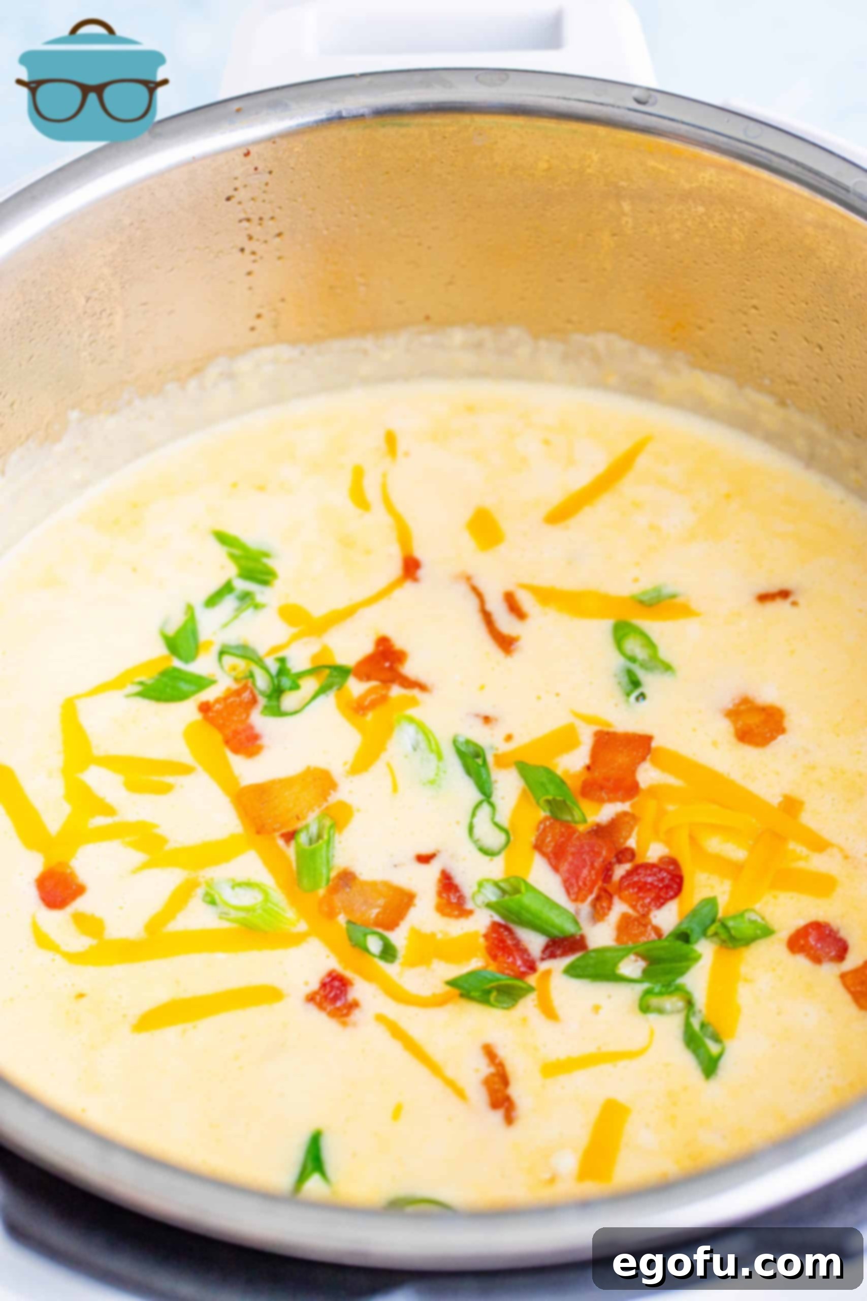 Finished Instant Pot Loaded Potato Soup, beautifully garnished with melted cheese, crispy bacon, and fresh green onions, served directly in the Instant Pot liner.
