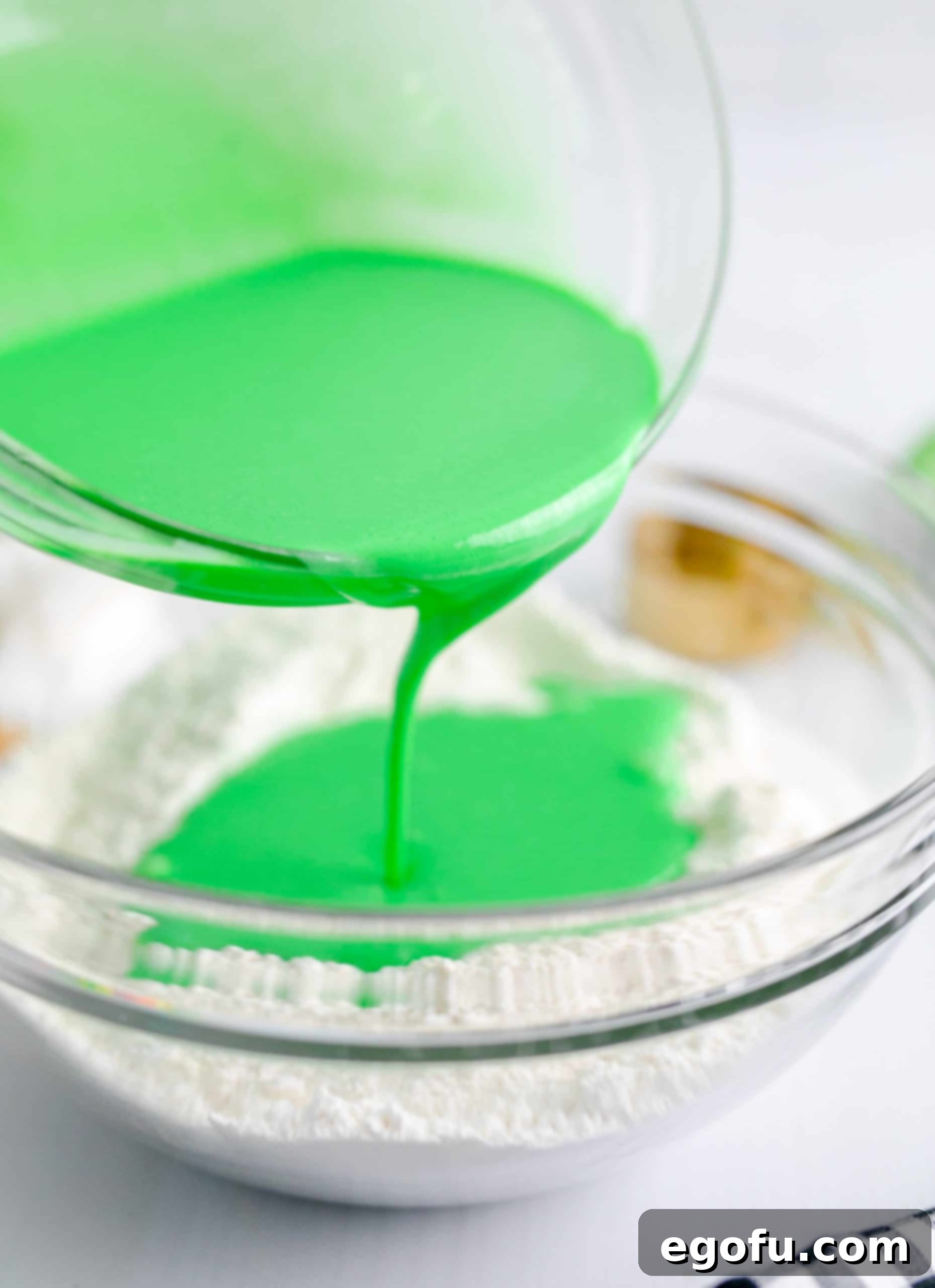 The vibrant green wet mixture being carefully poured into the well of the dry ingredients, initiating the creation of the pancake batter.