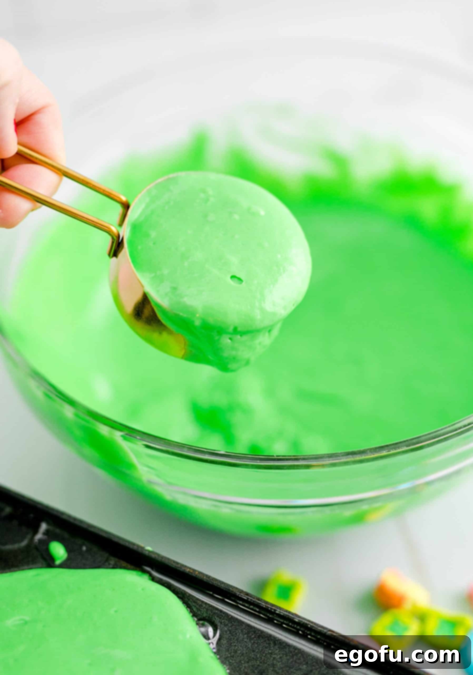 A quarter-cup measuring cup scooping out green pancake batter, indicating the consistent portion size for each pancake.