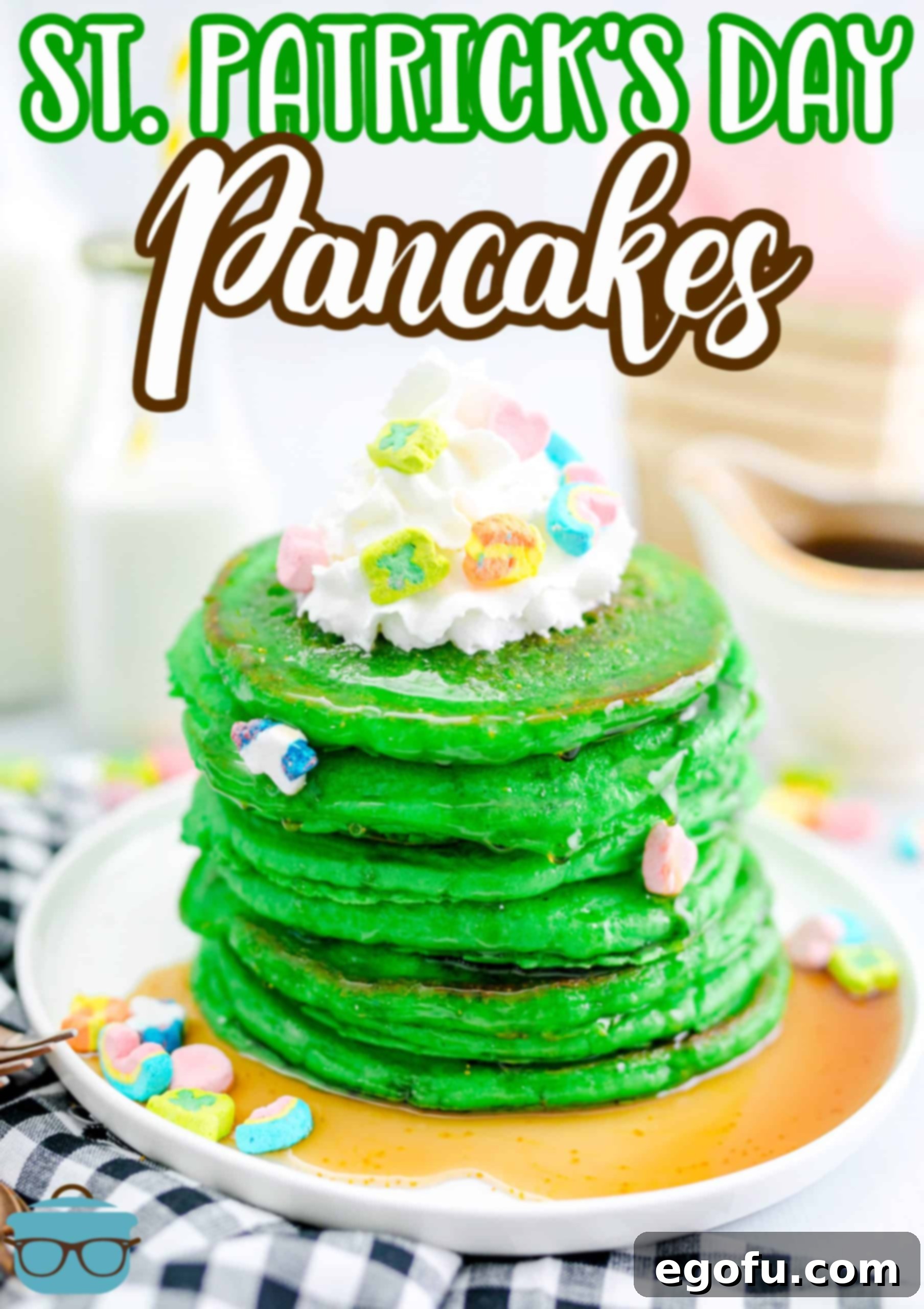Stacked St. Patrick's Green Pancakes on a plate, generously topped with fluffy whipped cream and colorful Lucky Charms marshmallows, making them extra festive.
