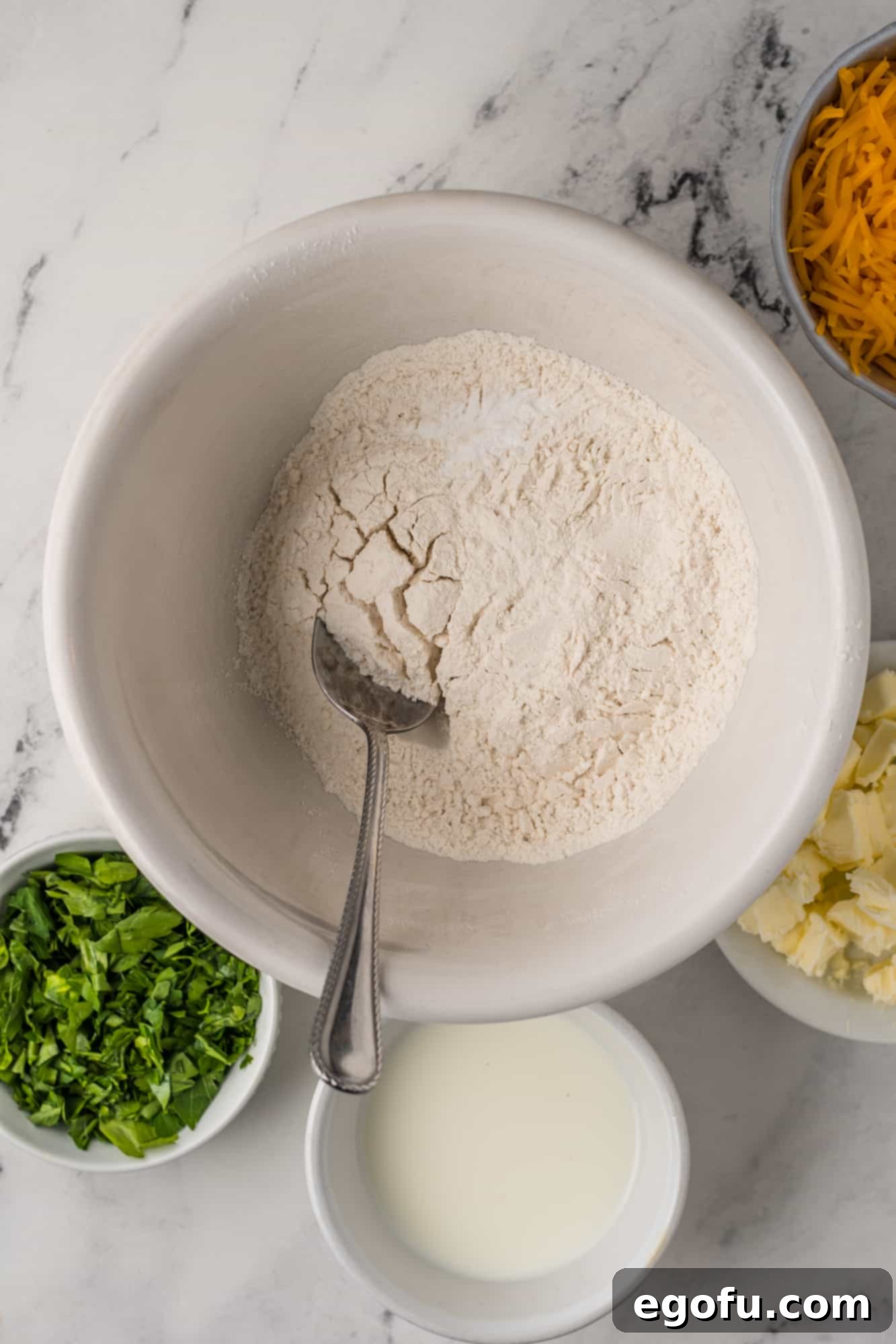 Flour and baking powder in bowl with a spoon.