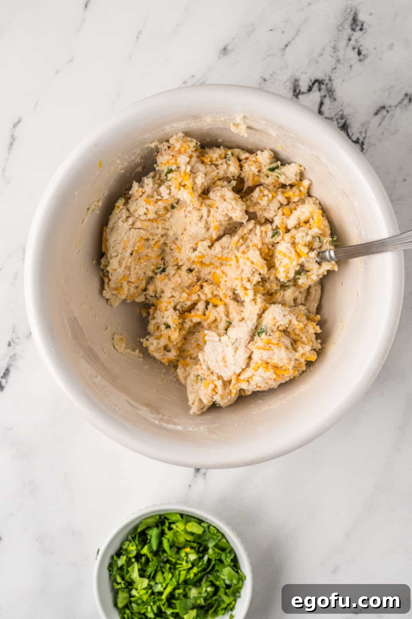 Dumplings being mixed up in a white bowl.