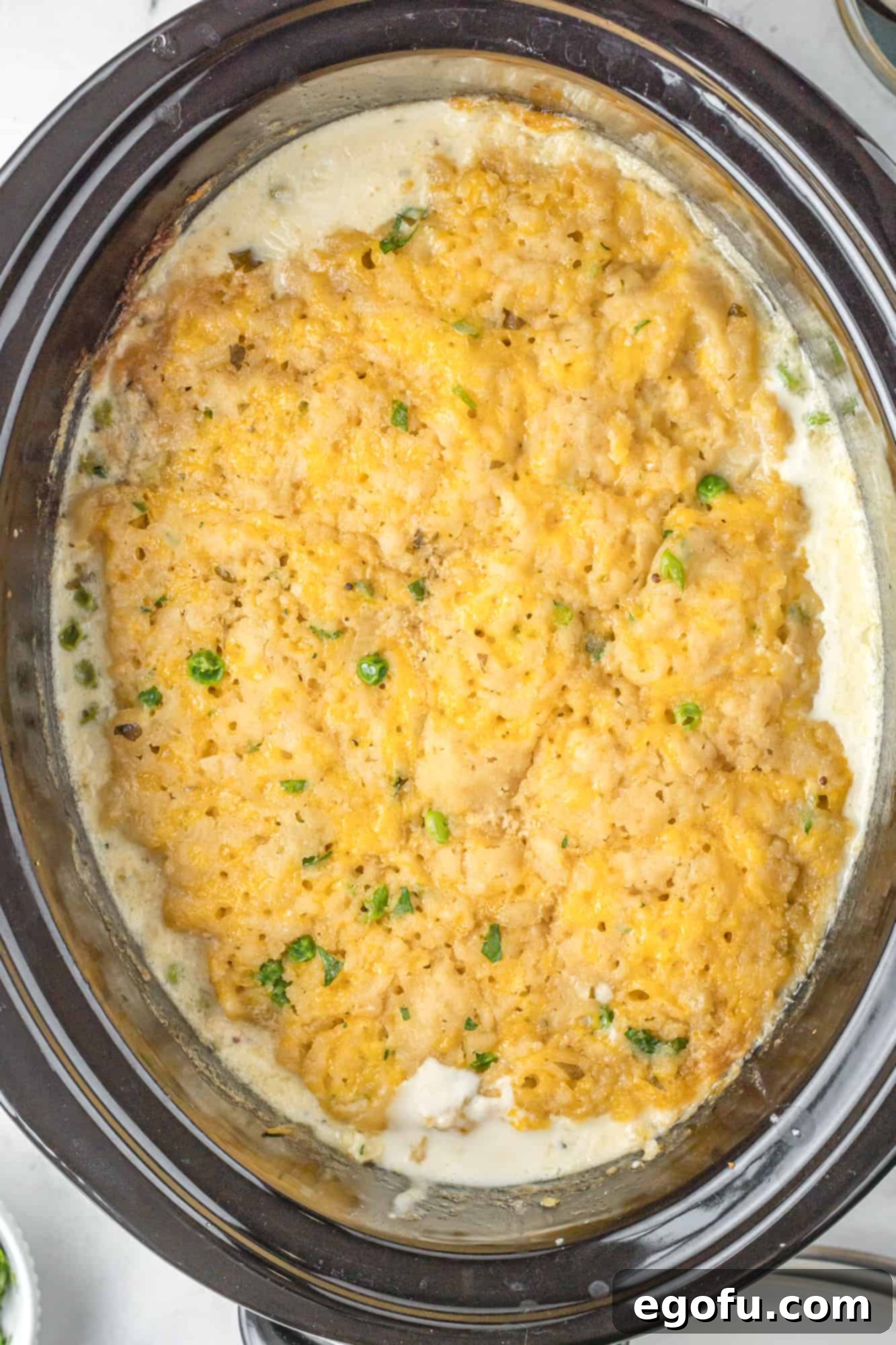 Finished Crock Pot Chicken and Cheddar Dumplings shown in an oval slow cooker.