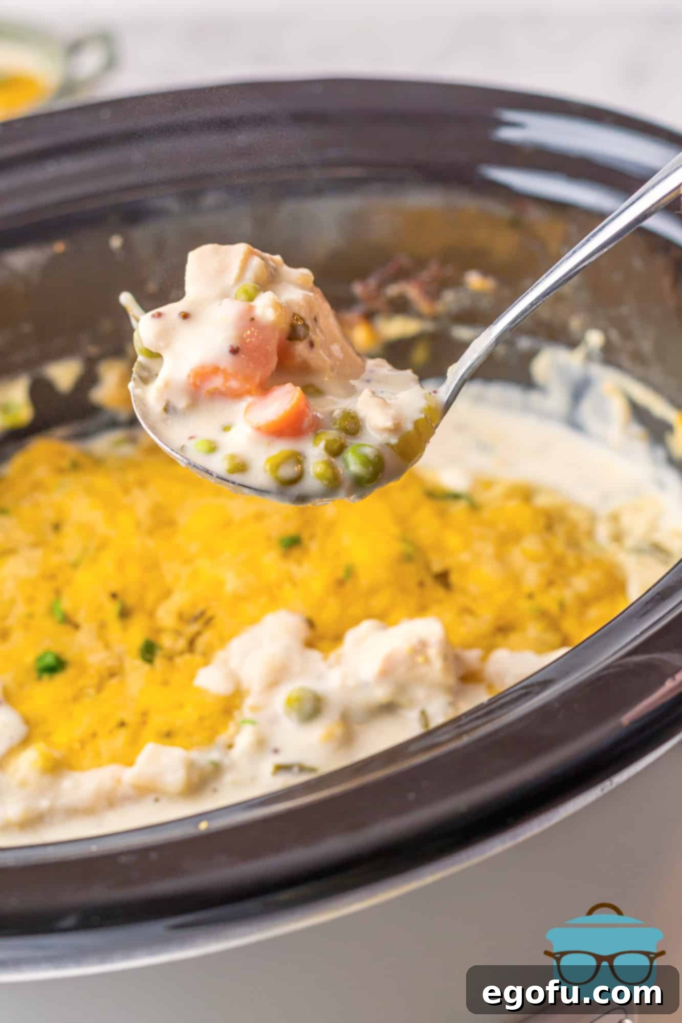 Ladle holding up some Crock Pot Chicken and Cheese Dumplings from pot.