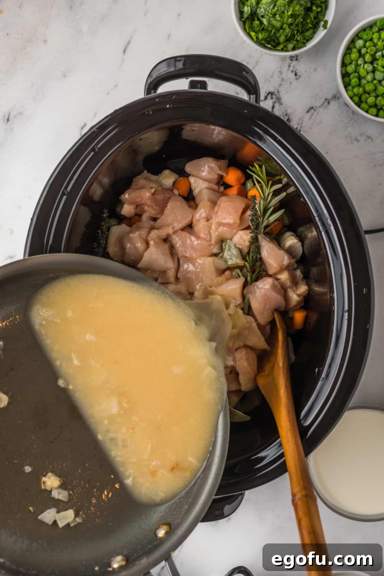Roux being poured over chicken mixture in crock pot.