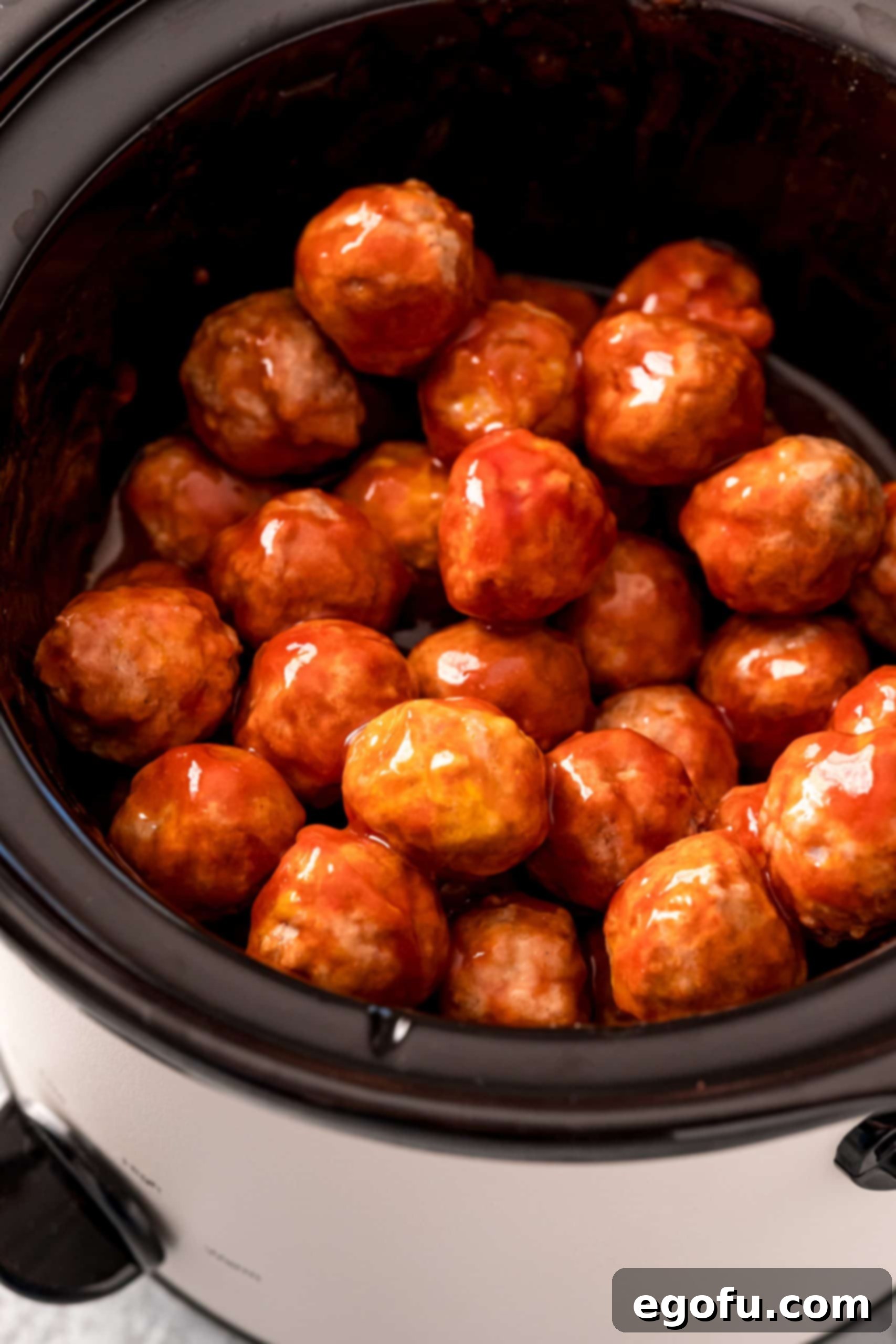 Slow Cooker Meatloaf Bites 6 Finished meatballs in crock pot, stirred and coated in sauce.