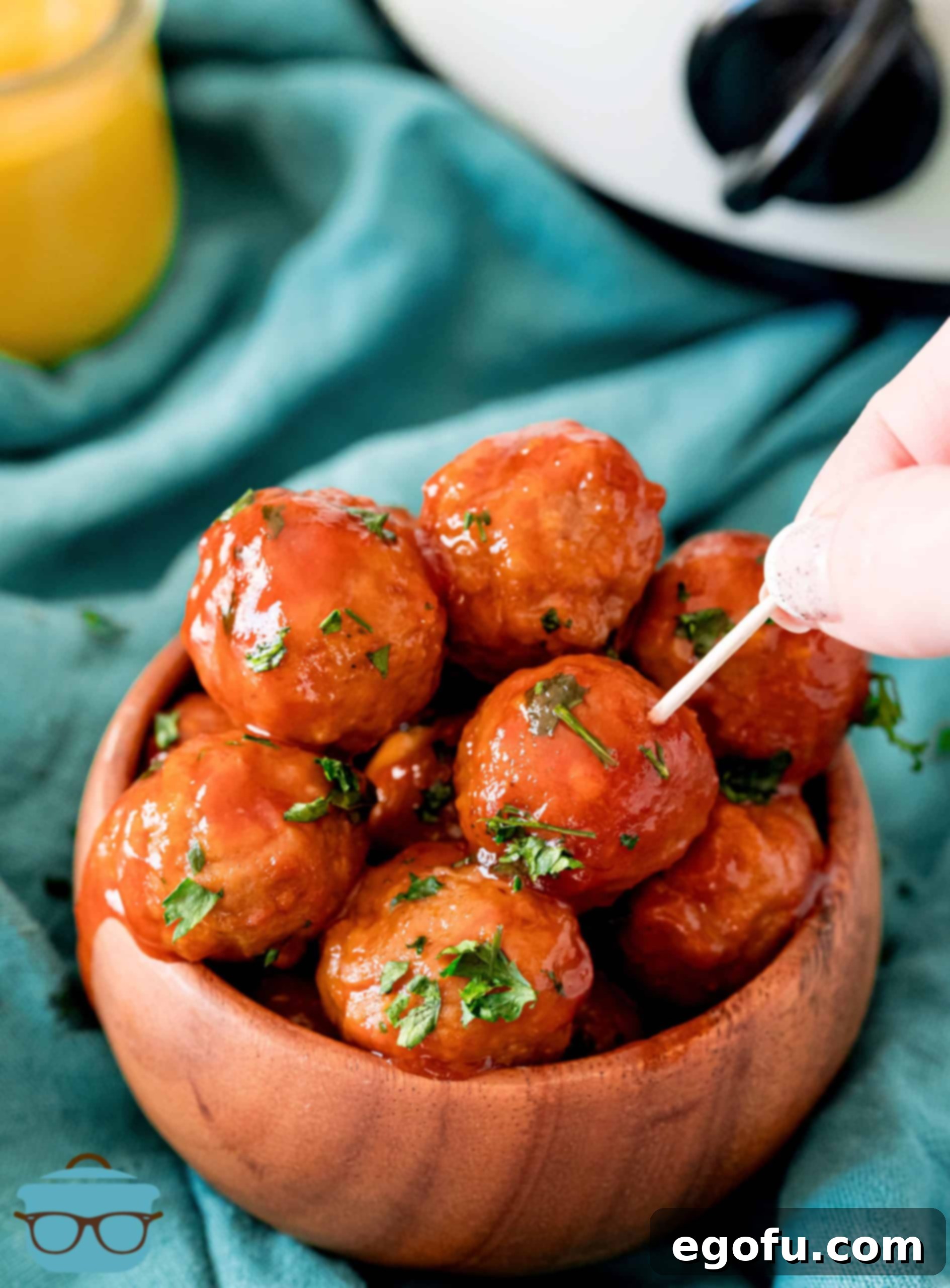 Slow Cooker Meatloaf Bites 7 Crock Pot Meatballs in a bowl with a hand poking one meatball with a toothpick, ready for serving.