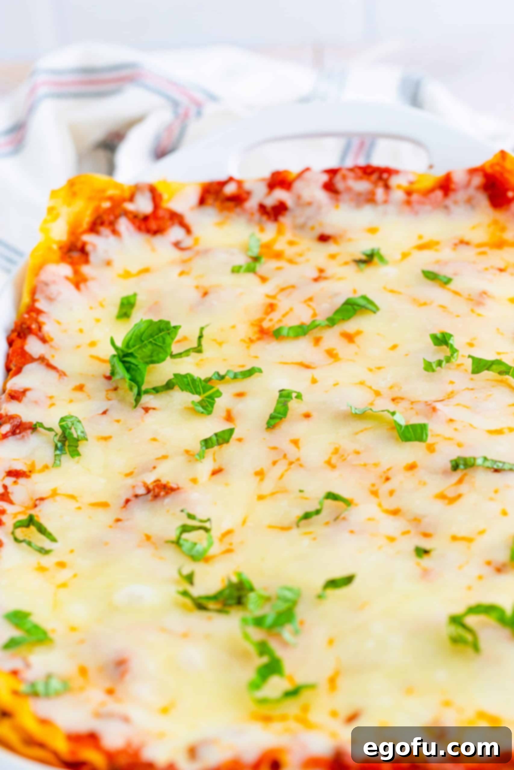 Hearty Homemade Lasagna Bake 9 Finished baked lasagna topped with basil close up in pan.