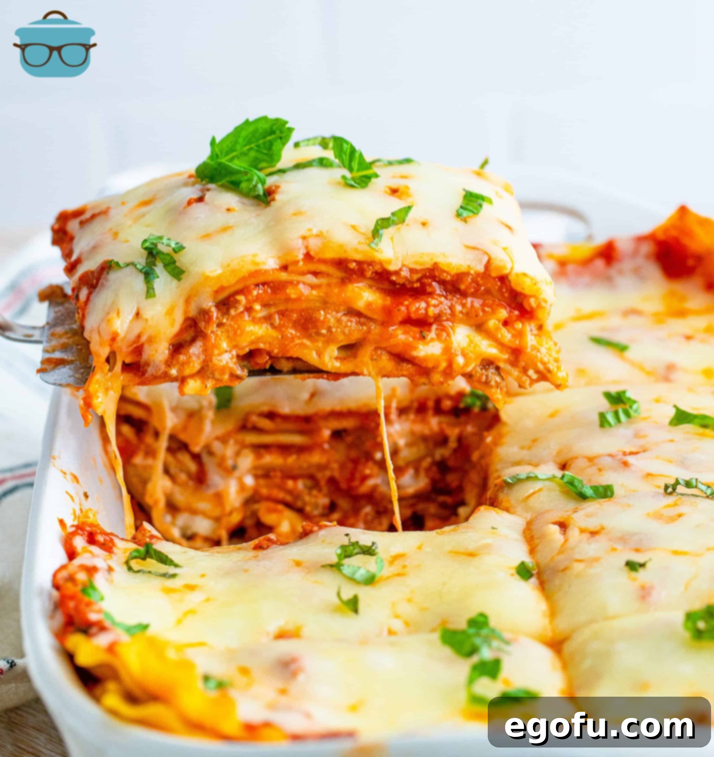 Hearty Homemade Lasagna Bake 10 Piece of Homemade Baked Lasagna being lifted out of baking dish.