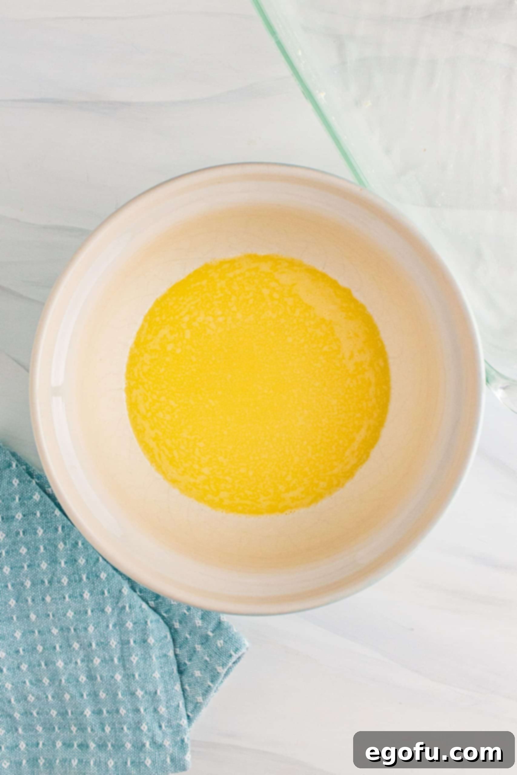 Grandma's No-Bake Peanut Butter Dream Bars 6 Perfectly melted butter in a white mixing bowl, ready for the next ingredients.