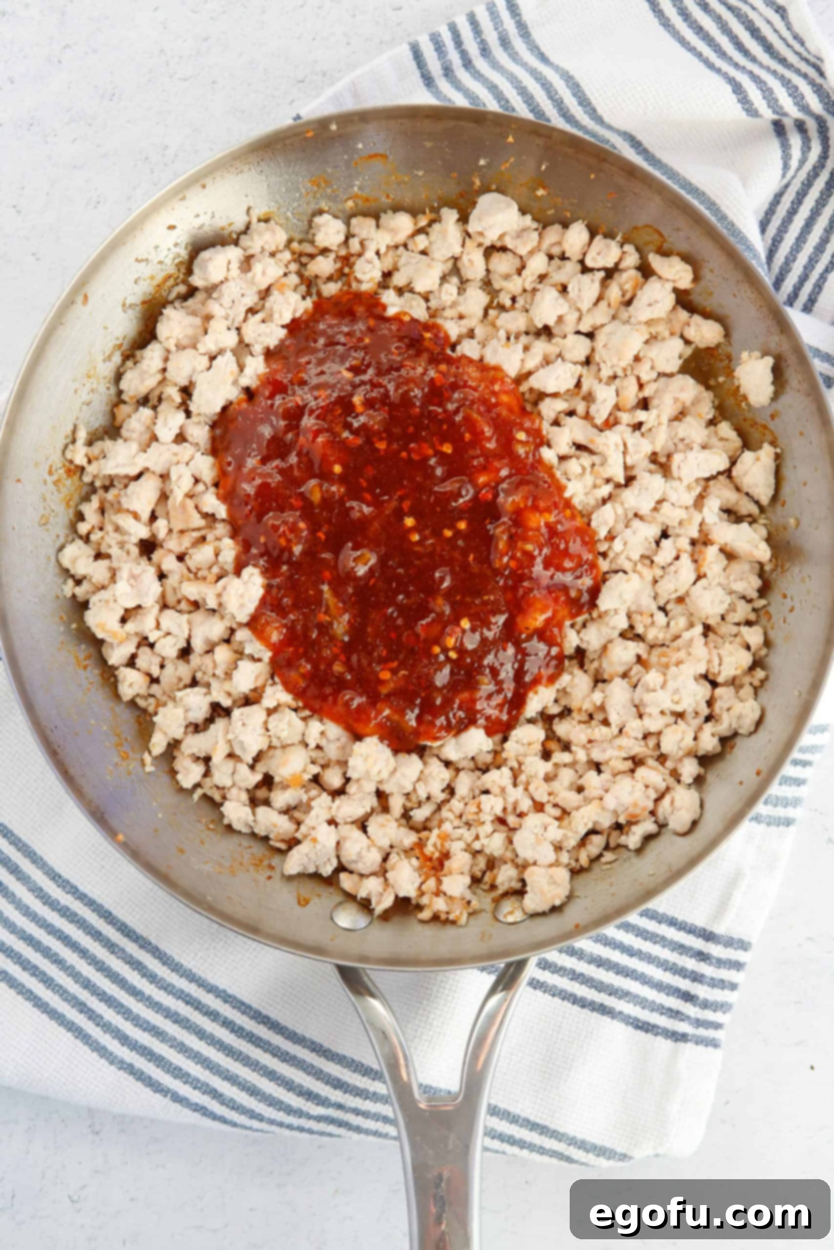 Skillet Orange Chicken Crumble 6 Cooked ground chicken, perfectly crumbled and browned in a skillet, with the rich orange sauce just added and ready to be stirred in.