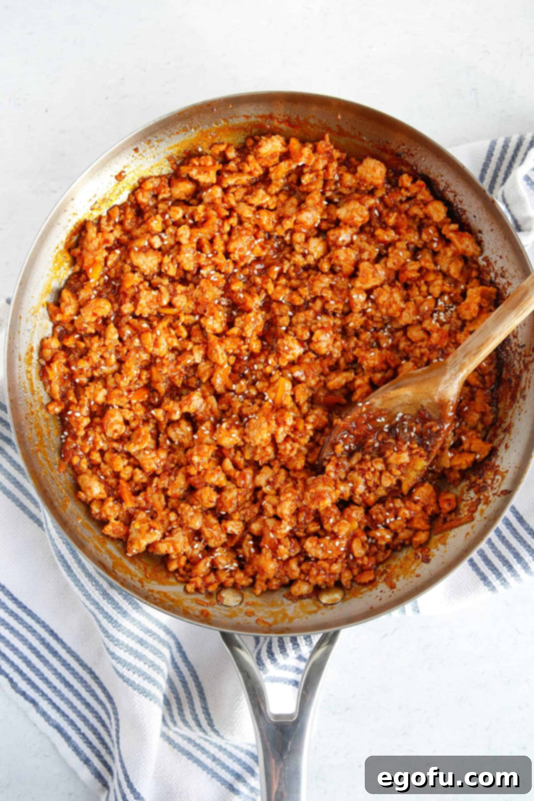 Skillet Orange Chicken Crumble 7 The savory ground chicken is completely coated in the thick, glossy orange sauce within the skillet, creating an irresistible aroma and appearance.