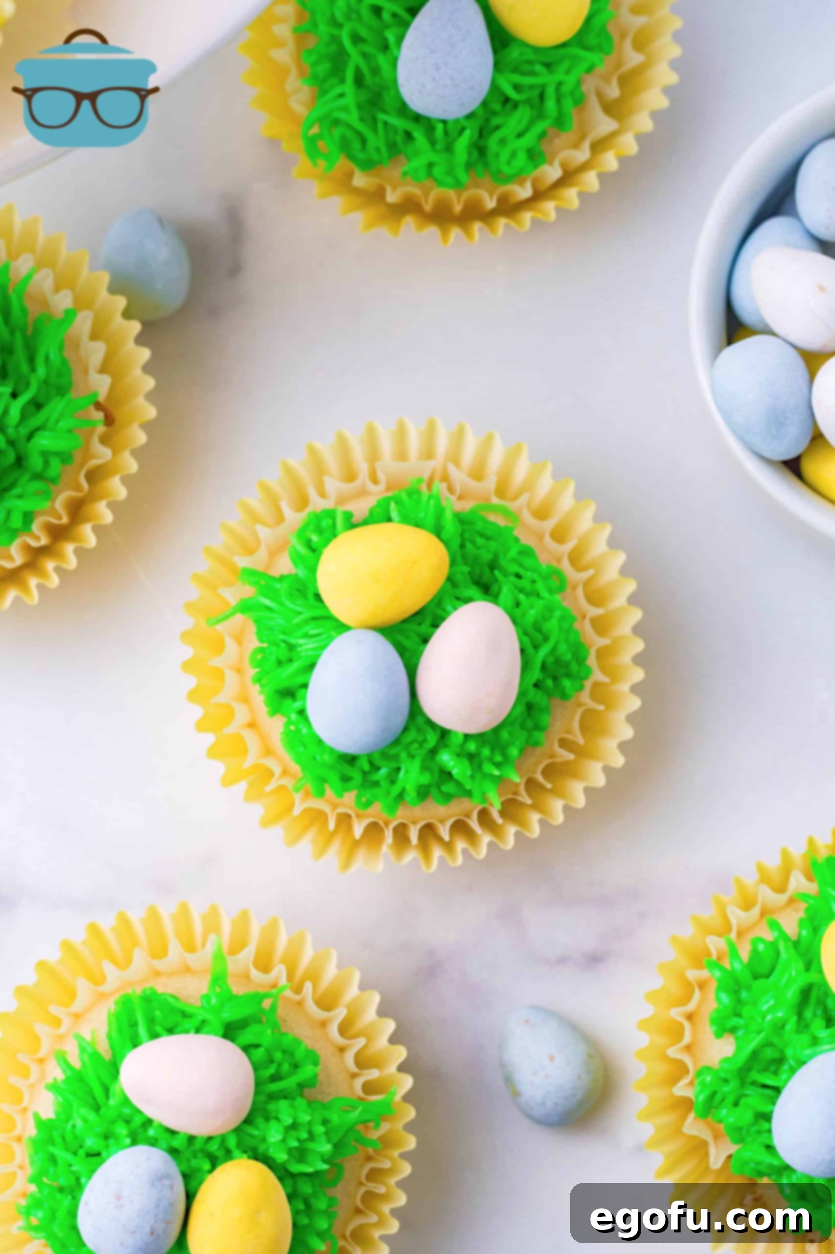 An overhead shot showcasing a platter of beautifully decorated Easter Egg Cupcakes on a rustic marble surface.