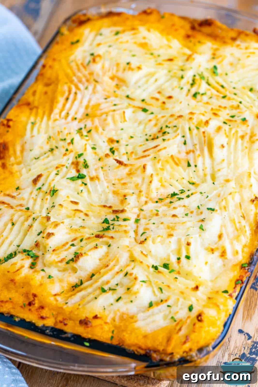 A perfectly baked Shepherd's Pie, golden and bubbling at the edges, beautifully garnished with fresh chopped parsley for a vibrant finish and enhanced aroma.