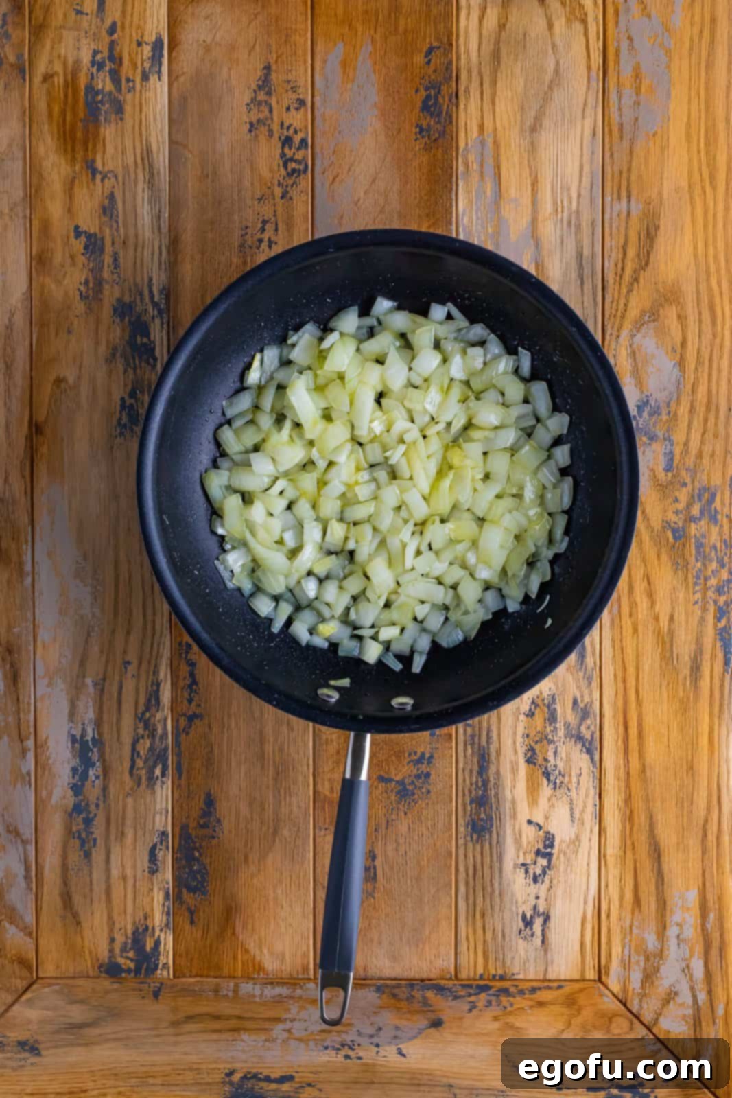 Diced sweet onions gently cooking in shimmering olive oil in a large, heated skillet, becoming soft and translucent, setting the aromatic base for the Shepherd's Pie.