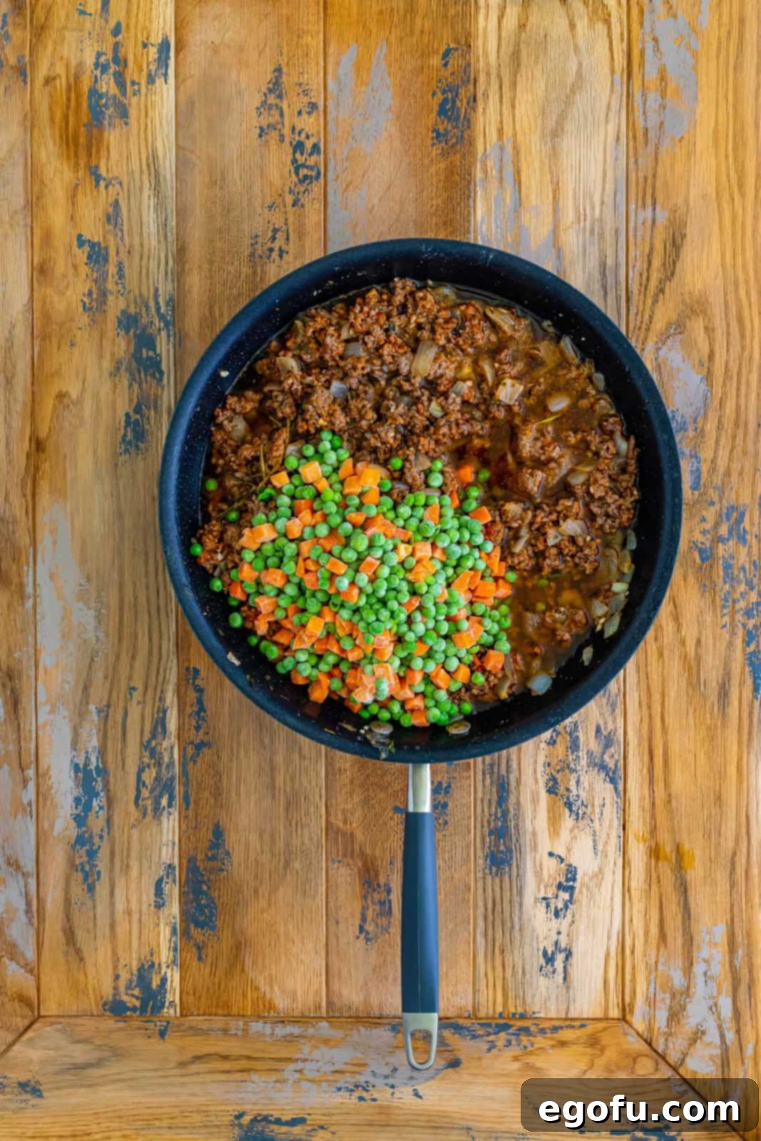Frozen peas and carrots and savory beef broth added to the skillet with the beef mixture, creating a vibrant and rich filling that will simmer to perfection.